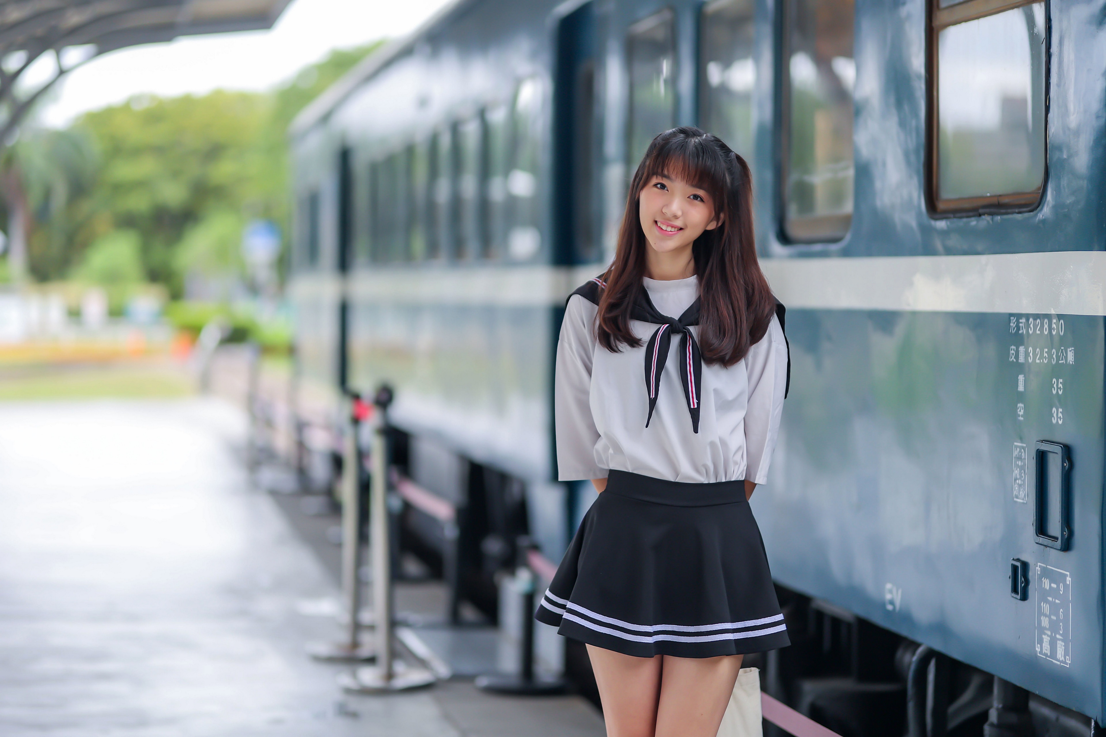 Asian schoolgirl in uniform at train station HD Wallpaper