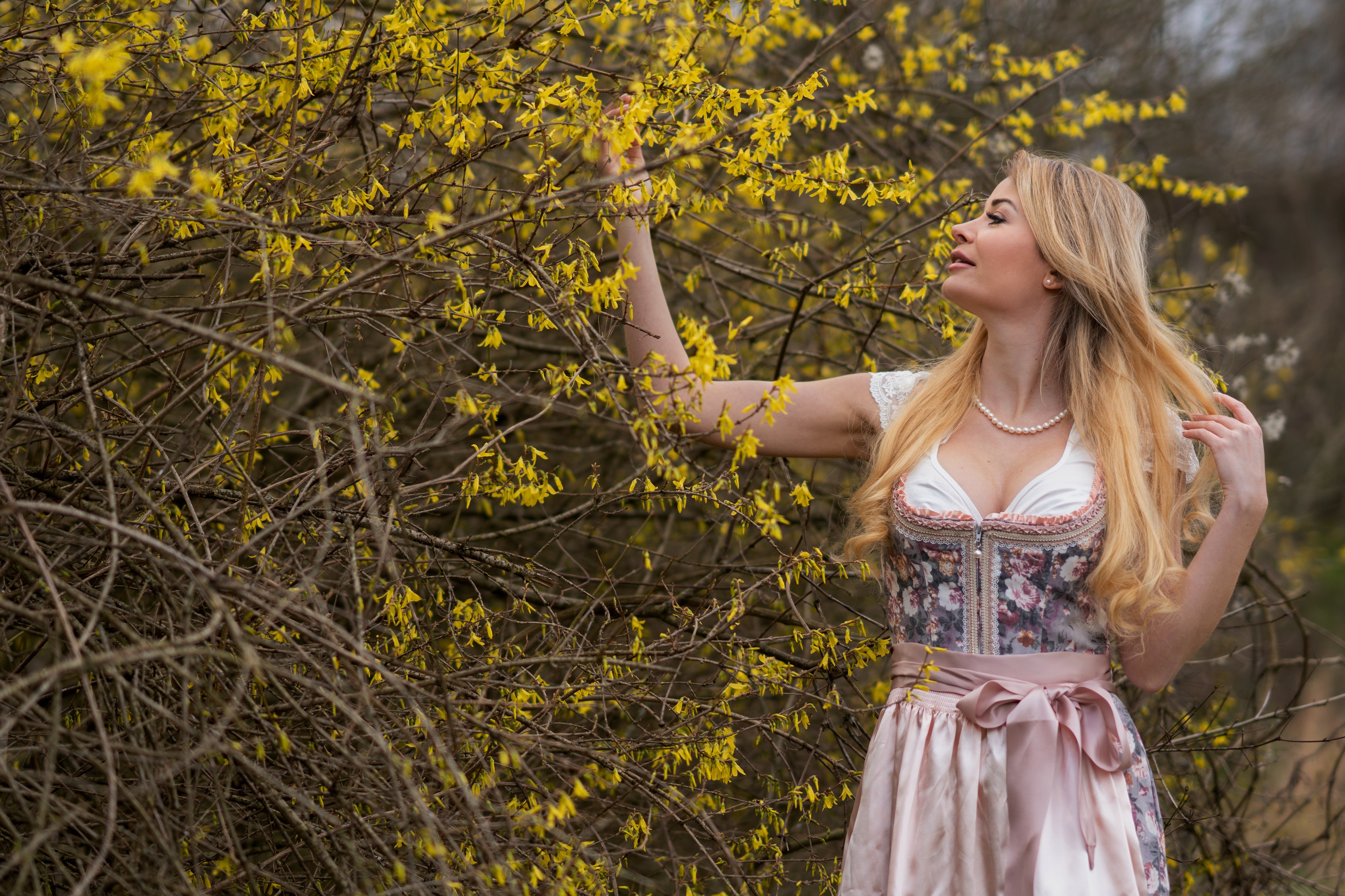 Blonde girl in traditional dress near flowering branches HD Wallpaper