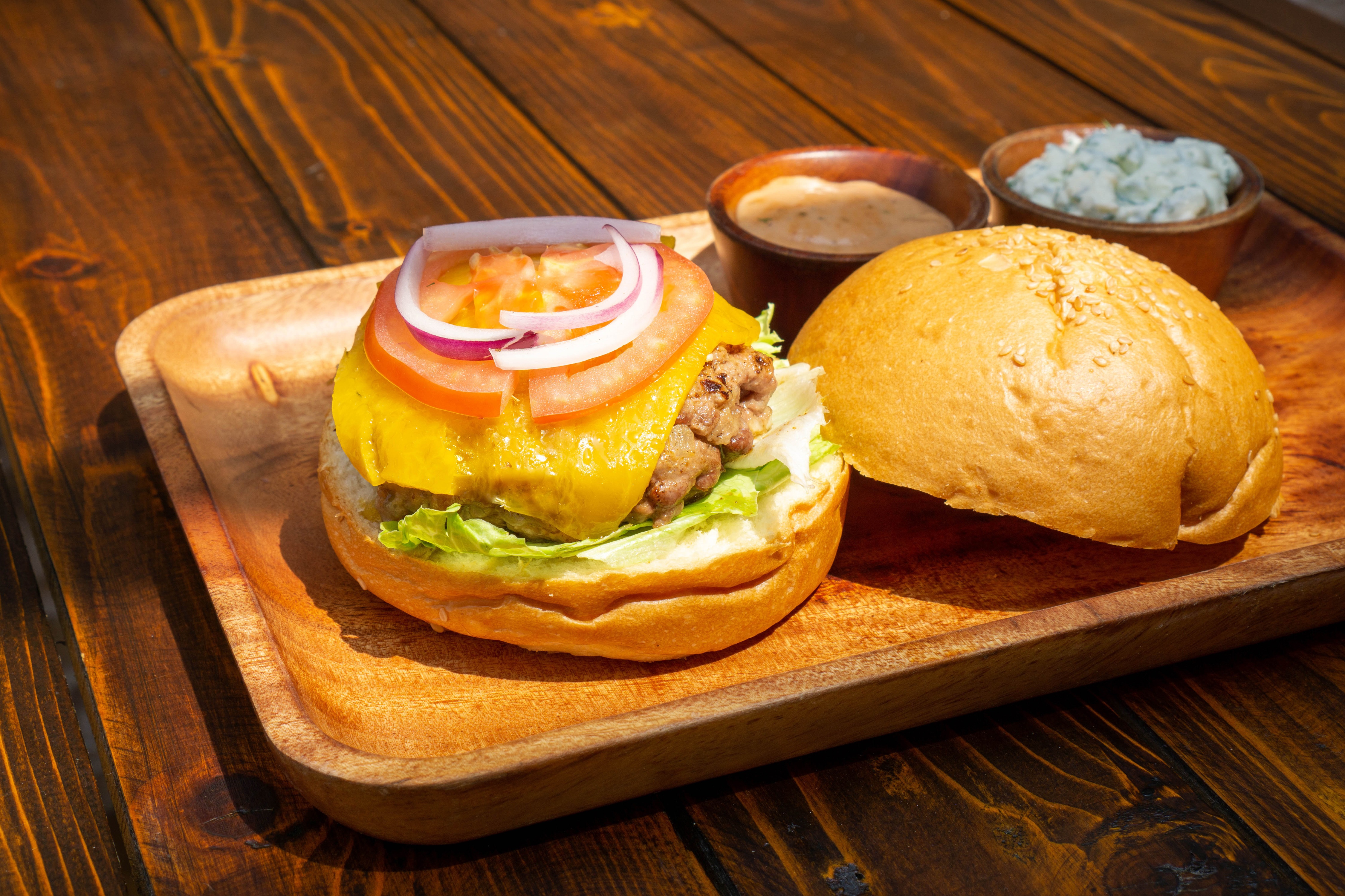 Hamburger with cheese, lettuce, tomato, and onion on a bun HD Wallpaper