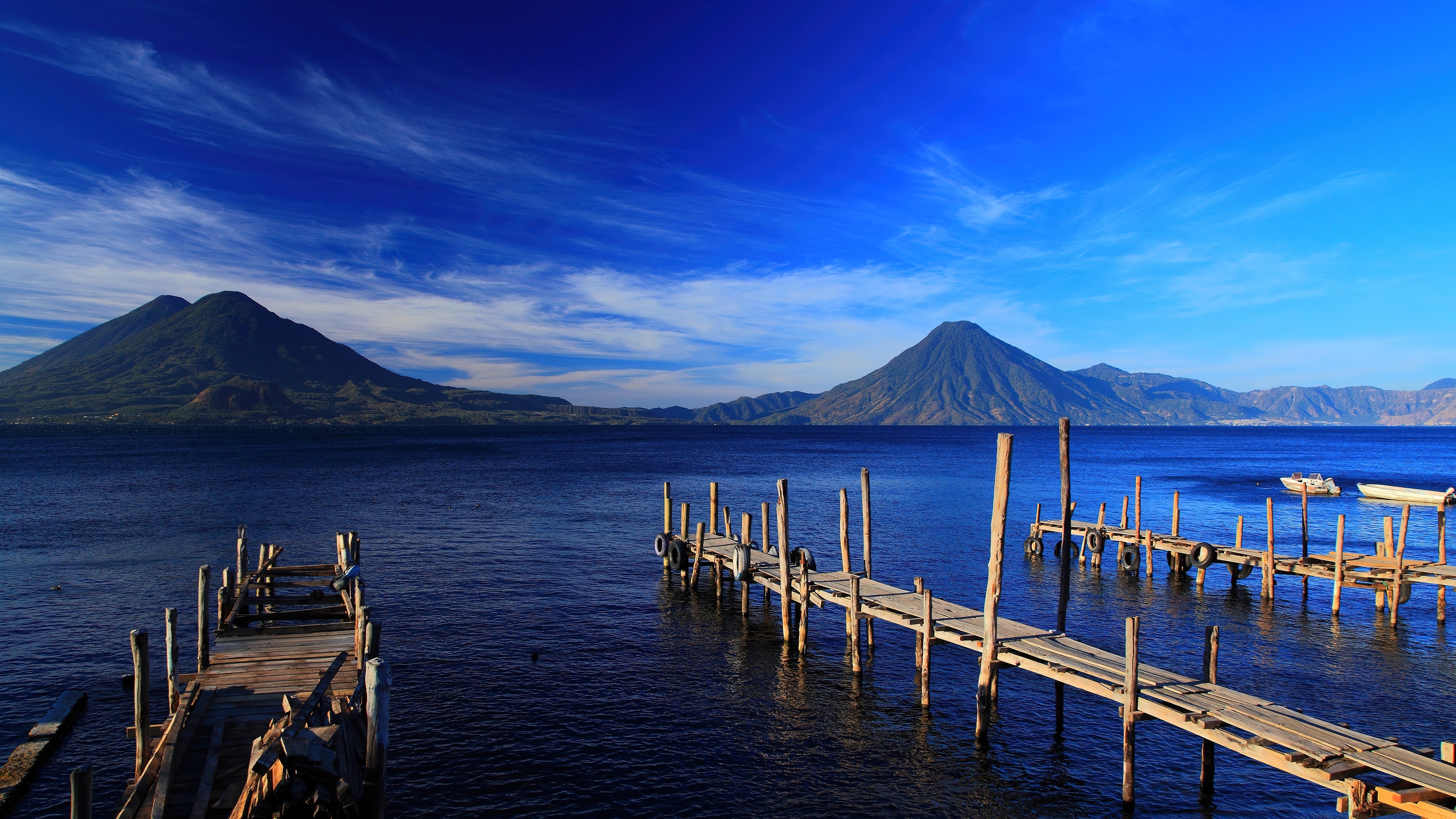 Wooden piers on a lake with mountains and blue sky 4K HD Wallpaper