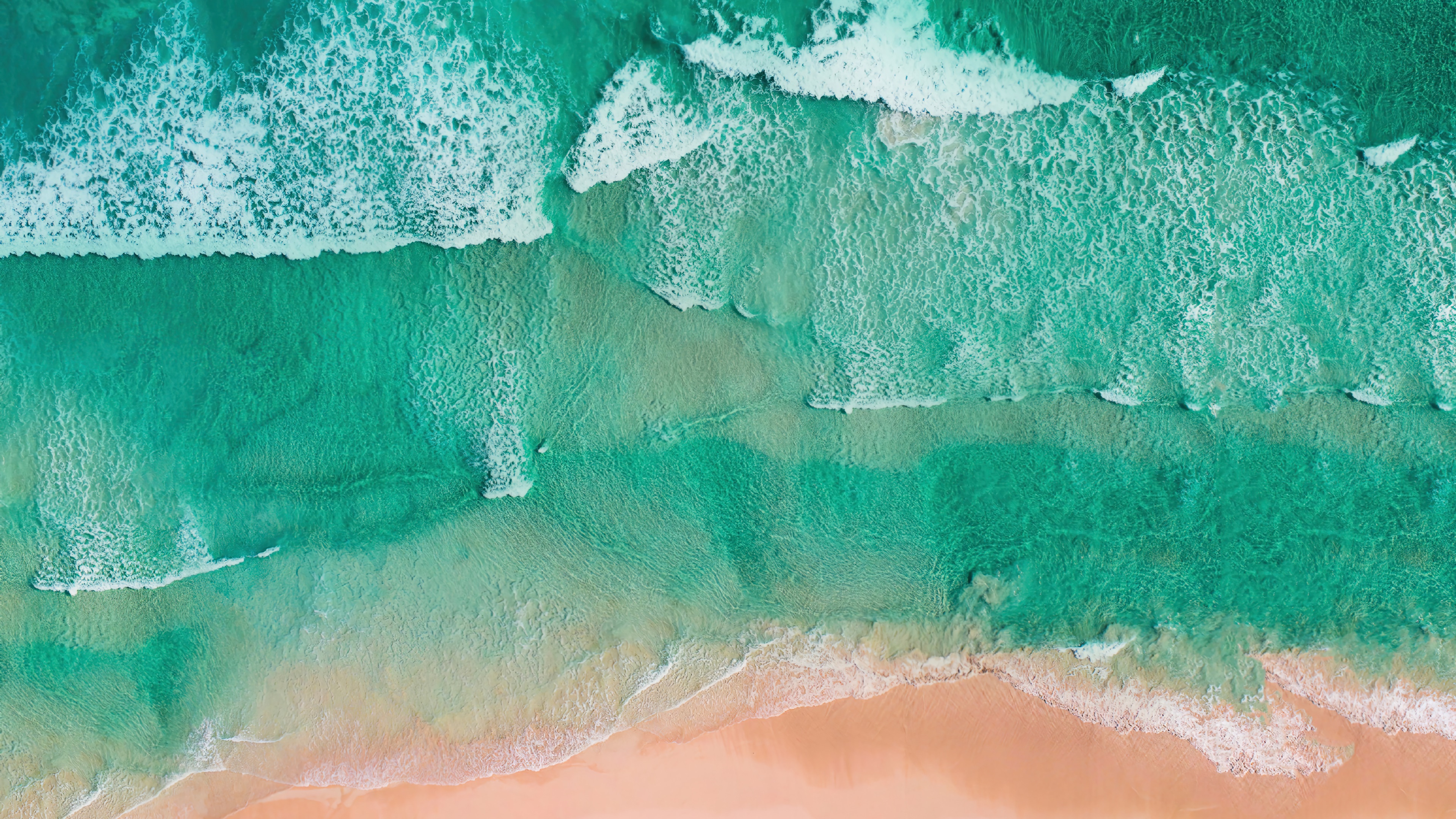 Aerial view of a beach with turquoise waves and sand HD Wallpaper