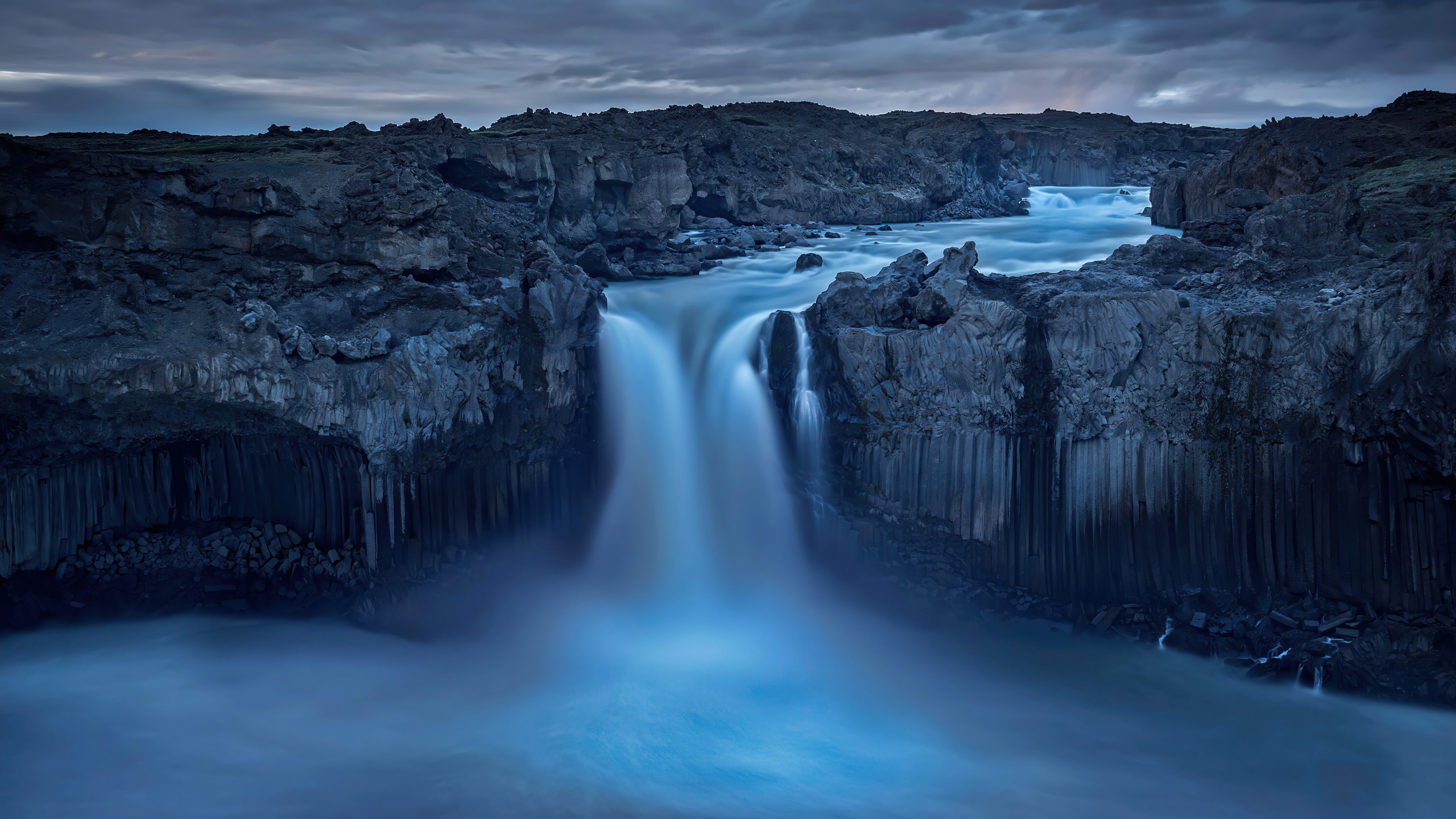 Waterfall in a rocky canyon with dramatic clouds HD Wallpaper