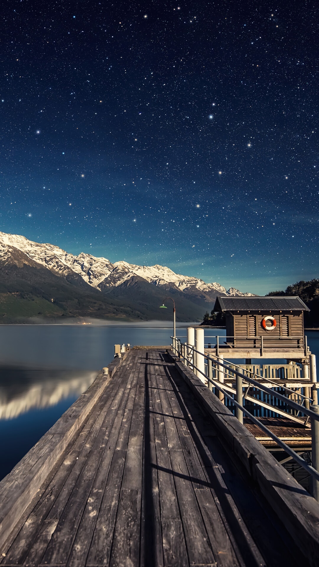 Wooden pier under starry sky with snow-capped mountains and lake HD Phone Wallpaper