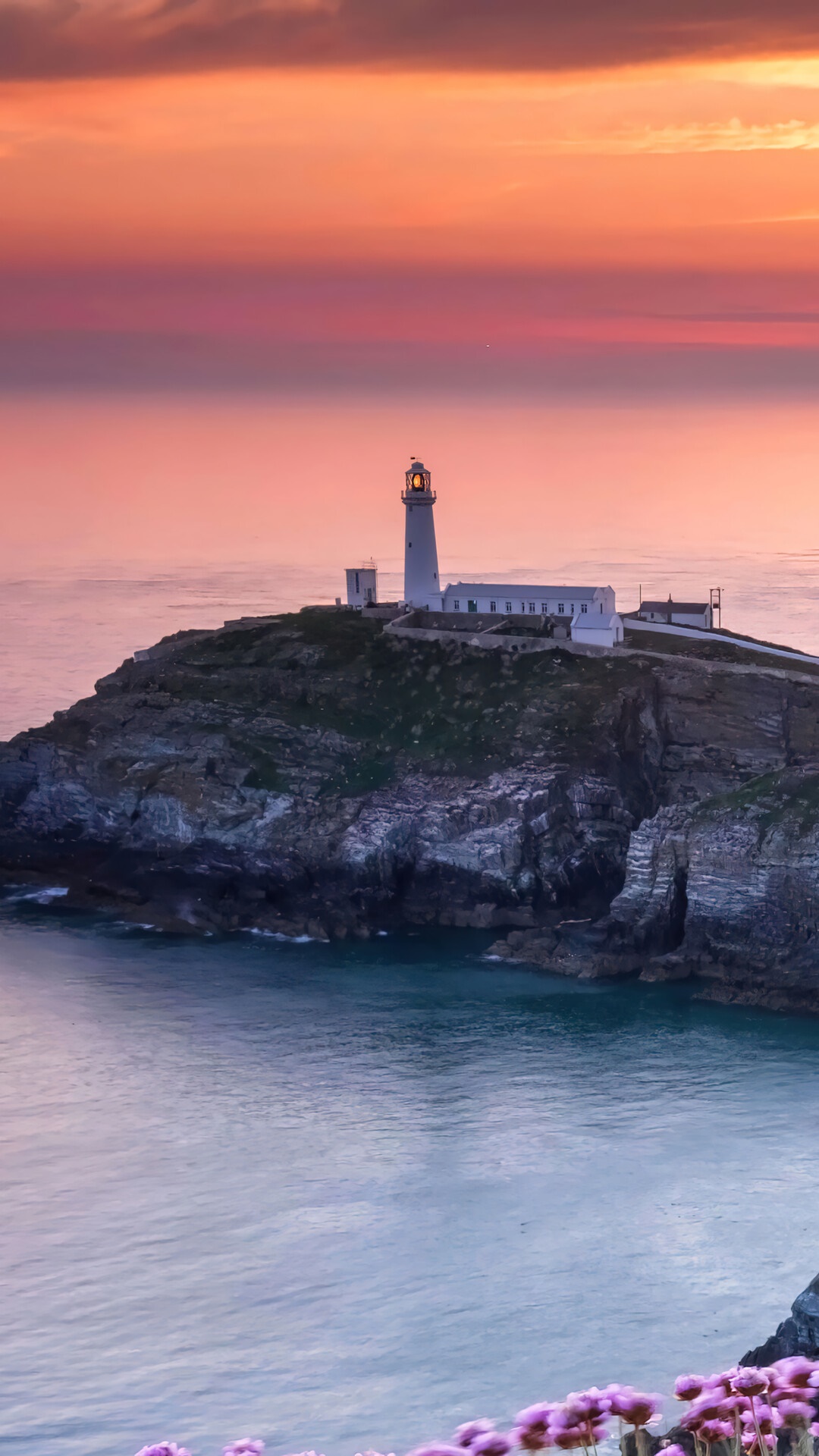 Lighthouse on a rocky coast at sunset HD Phone Wallpaper