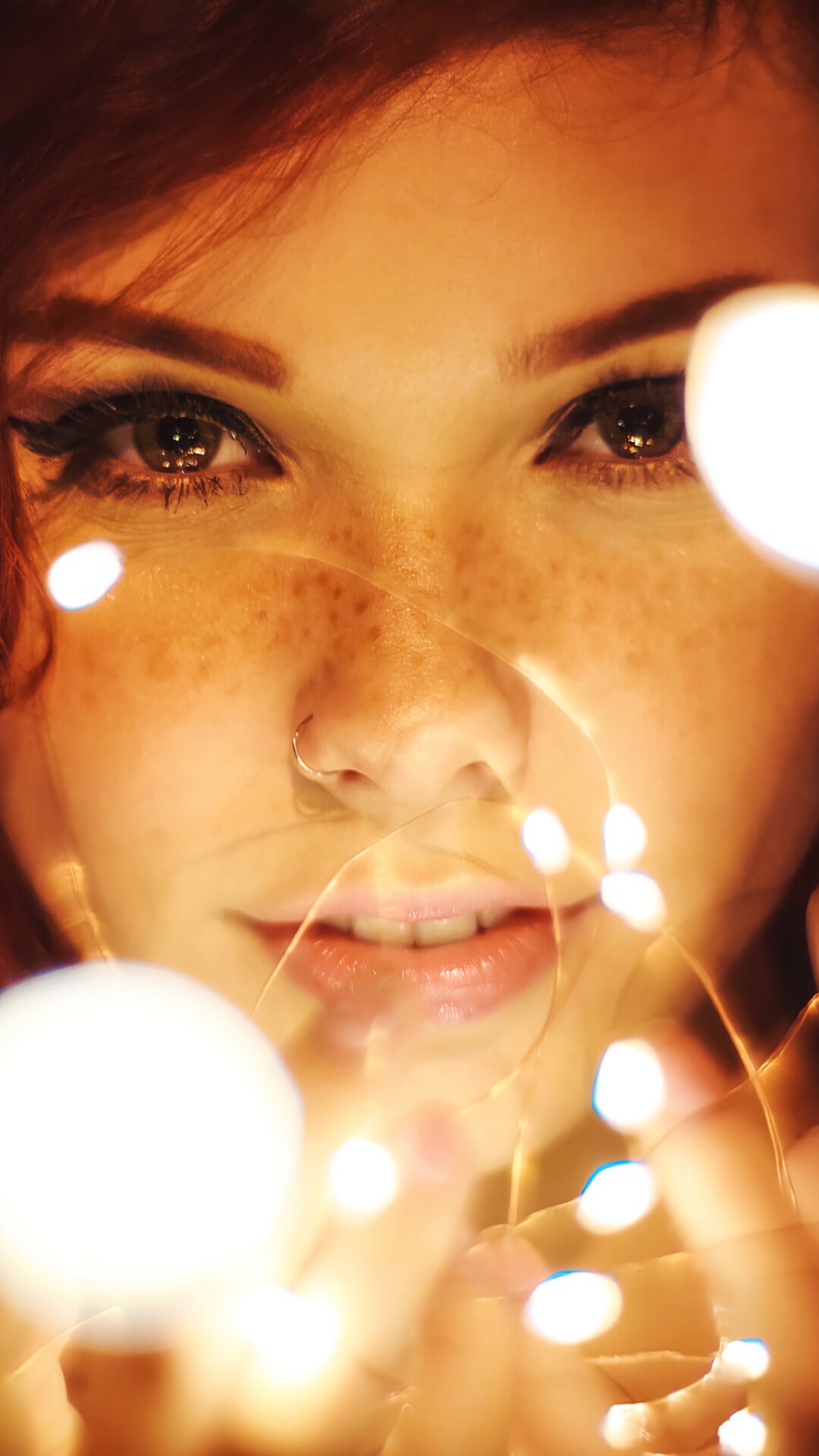Woman with freckles and fairy lights HD Phone Wallpaper