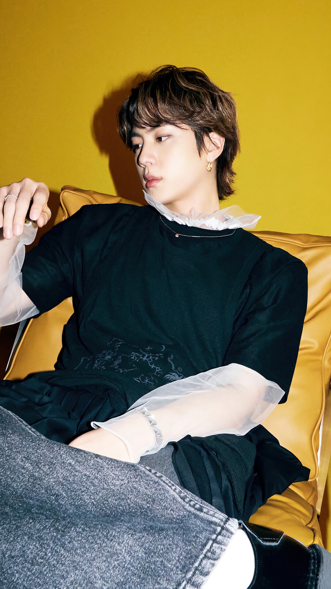 Jin from BTS posing on a yellow couch HD Phone Wallpaper