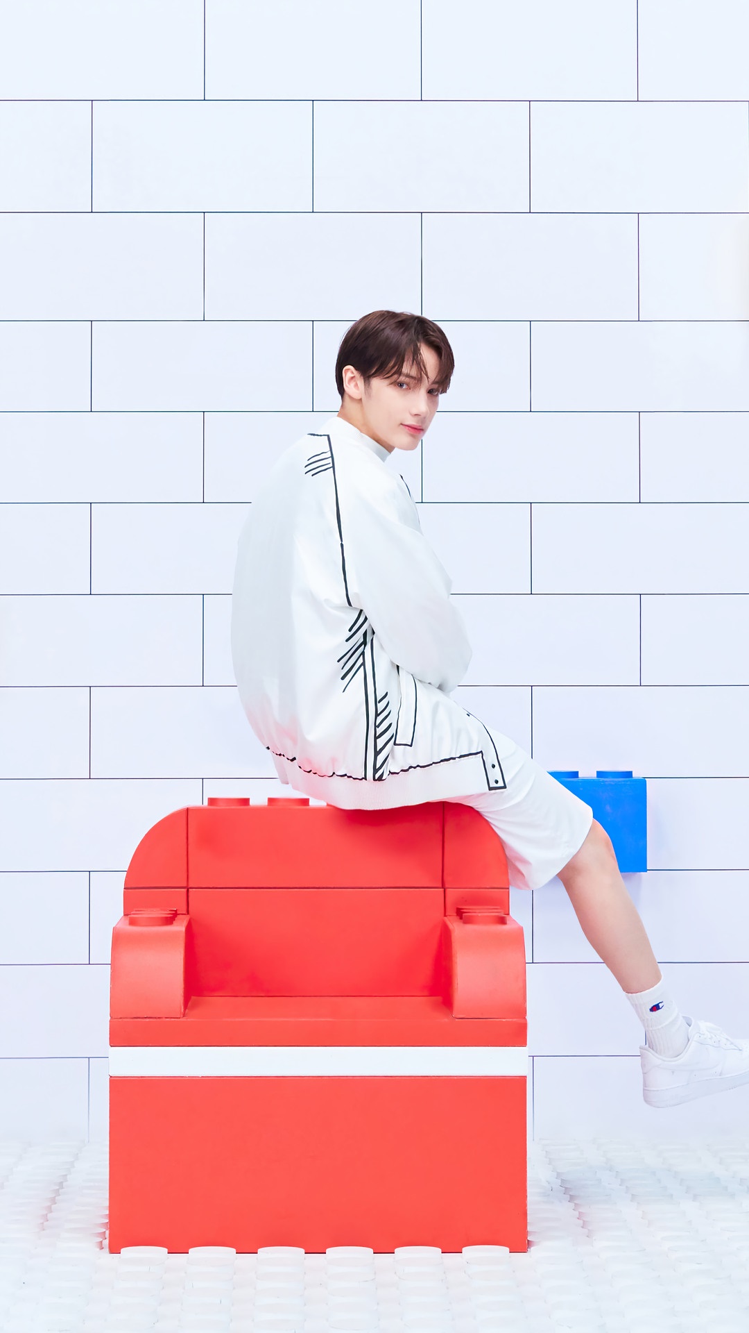 Huening Kai from TXT sitting on a red Lego chair HD Phone Wallpaper