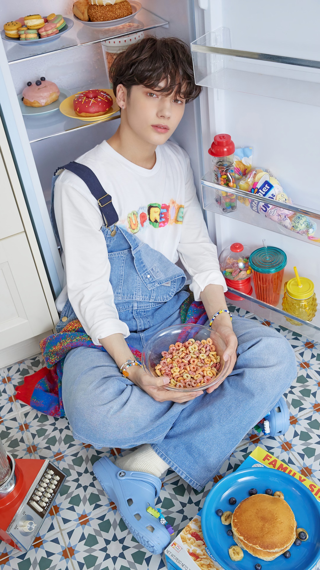 Huening Kai from TXT sitting by a refrigerator HD Phone Wallpaper