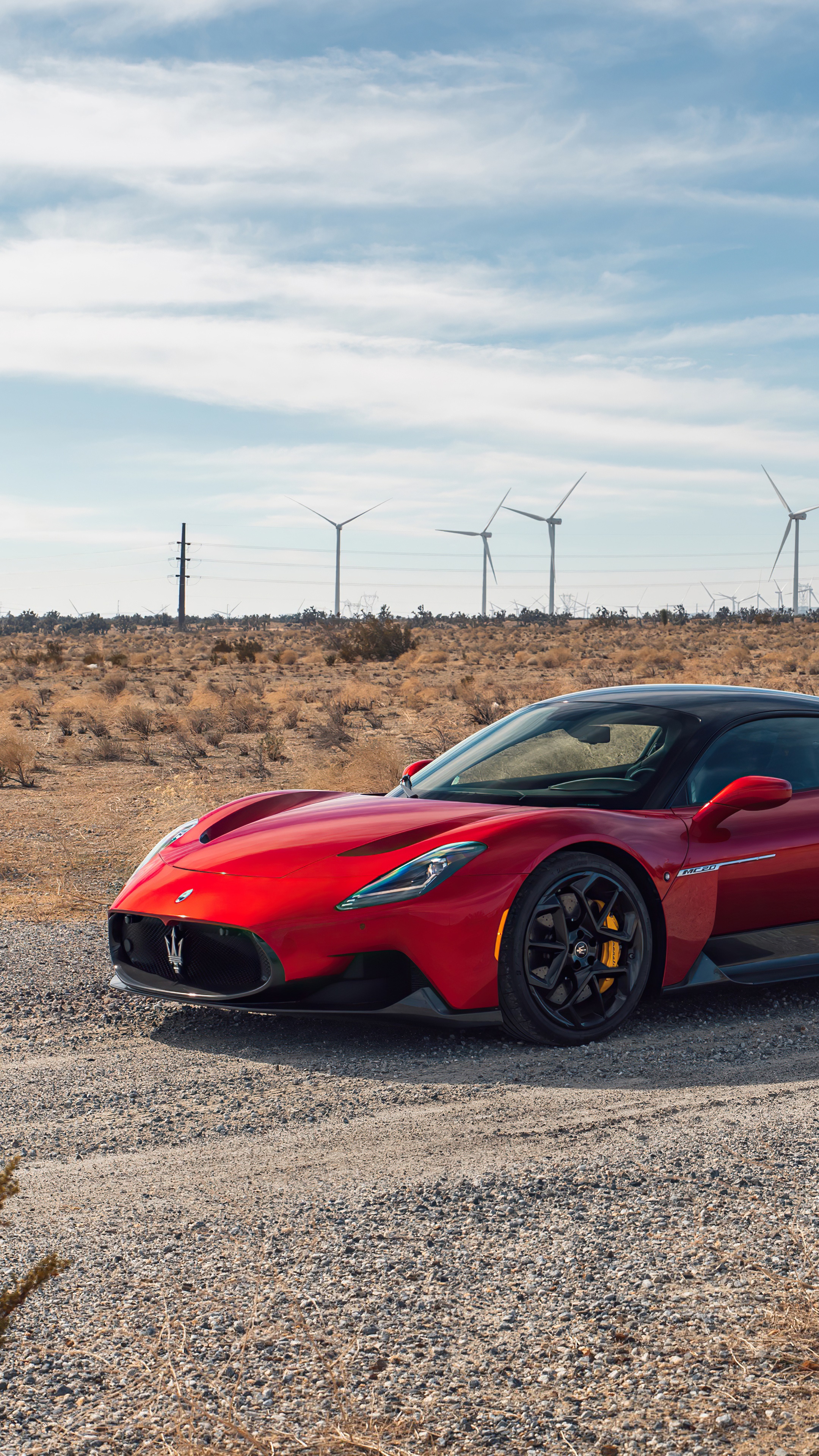 Red Maserati MC20 in a desert landscape with wind turbines HD Phone Wallpaper