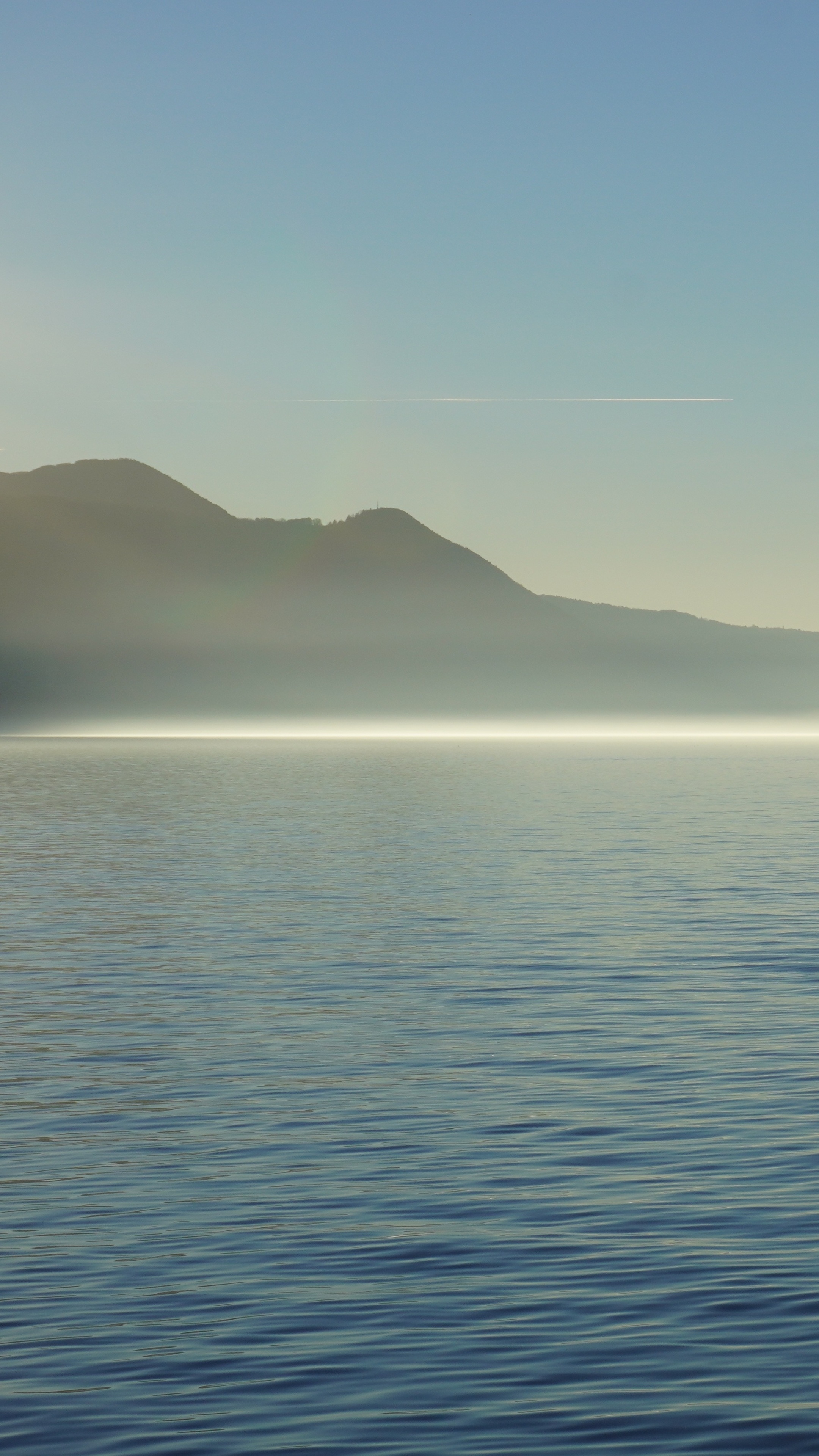 Lake and mountains with fog and airplane contrail HD Phone Wallpaper