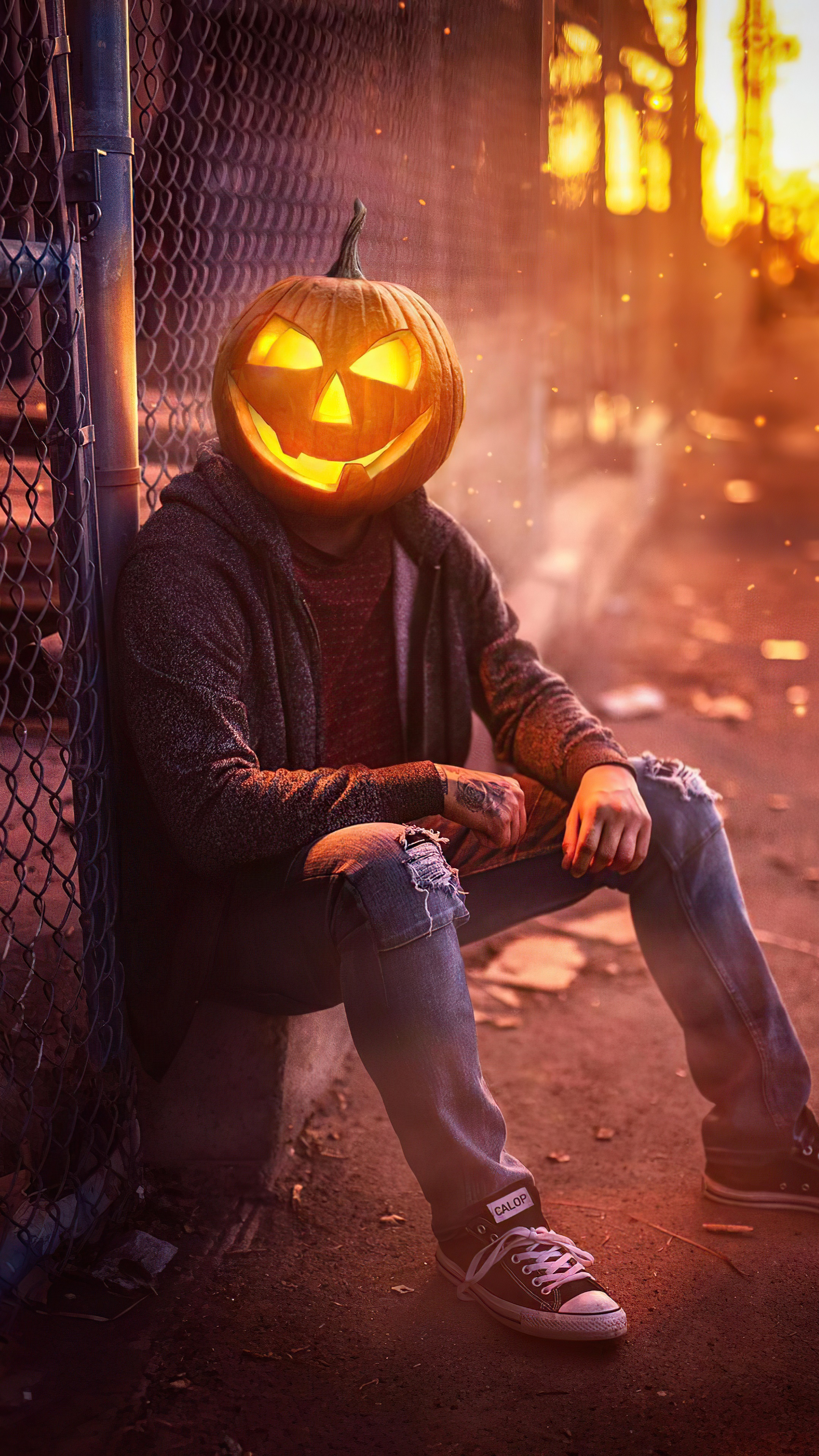 Person with Jack-o'-lantern head sitting by fence HD Phone Wallpaper