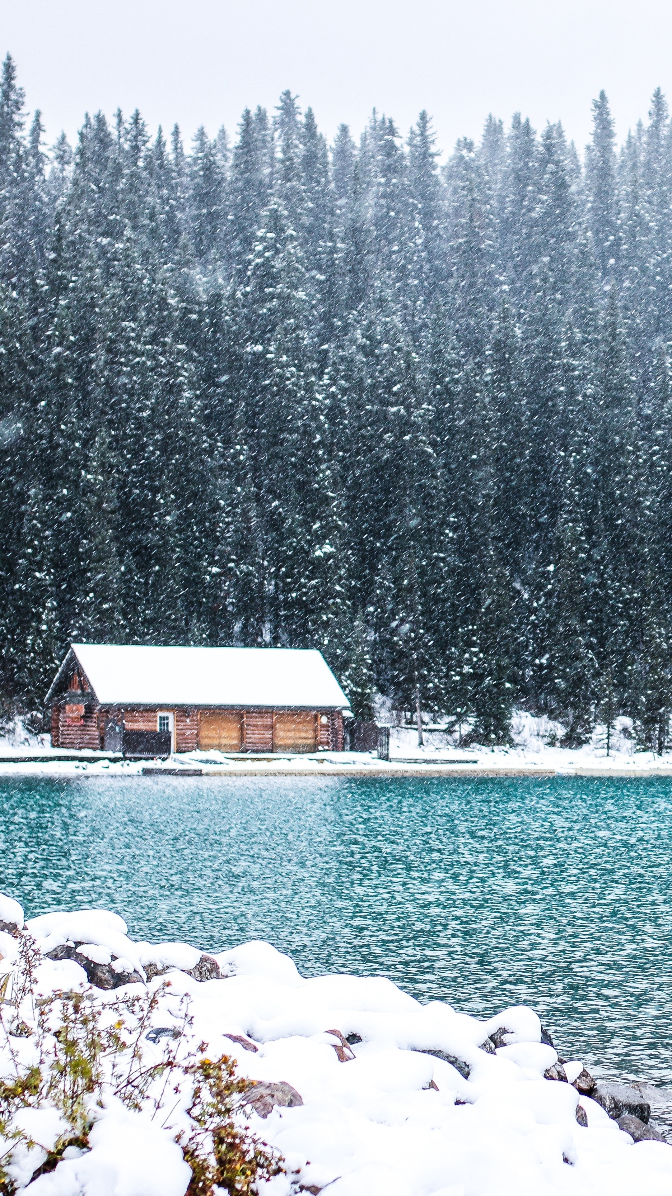 Log cabin on a lake in Canada during snowfall HD Phone Wallpaper