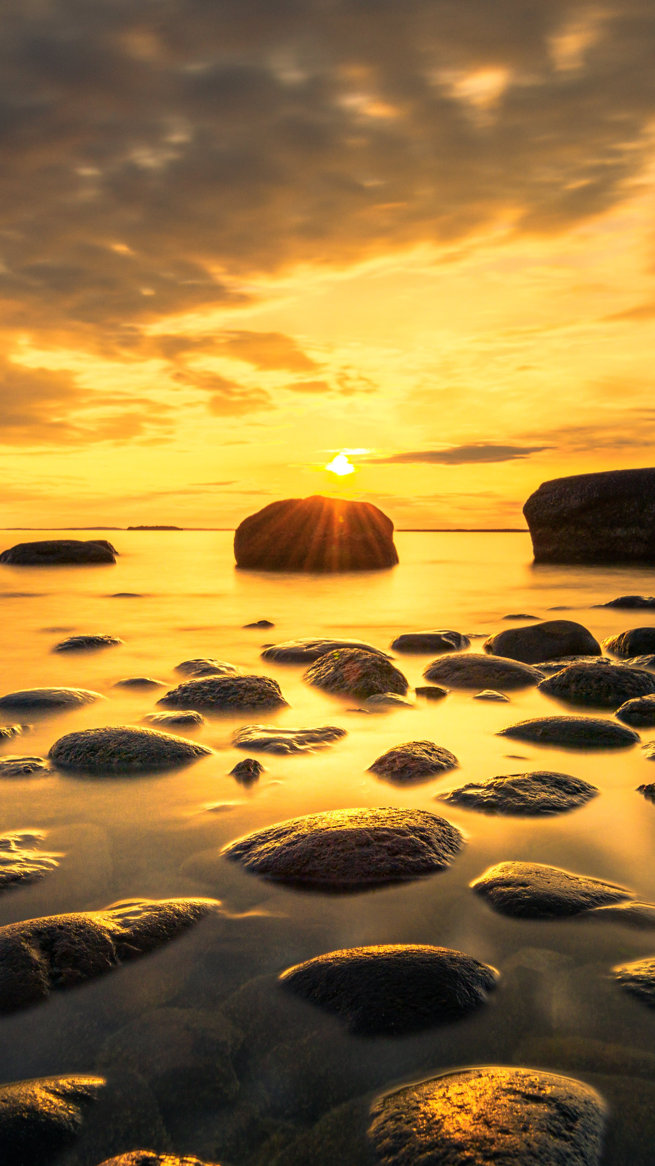 Sunset over a rocky shore with calm water HD Phone Wallpaper