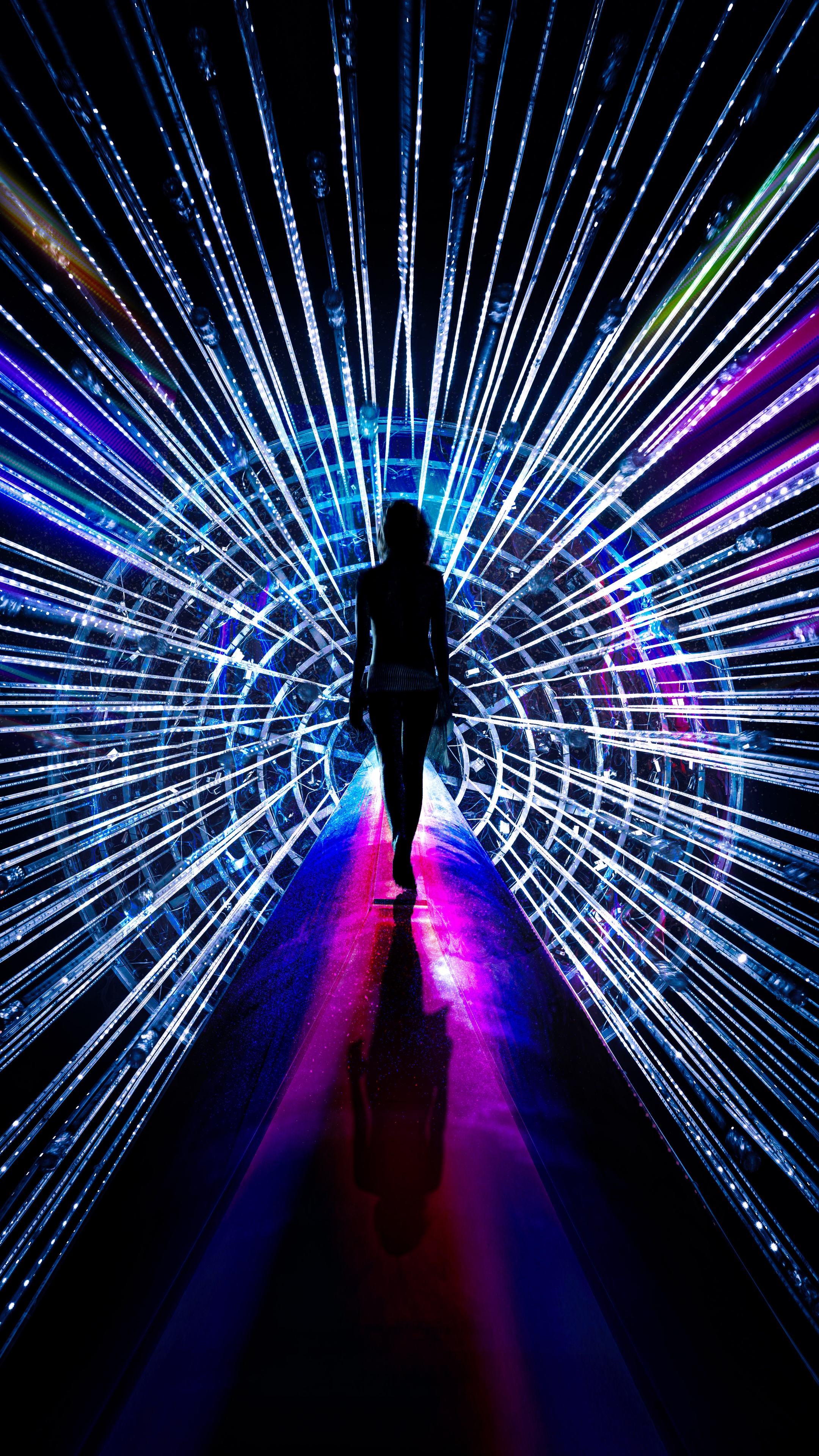 Silhouette of a person walking through a tunnel of lights HD Phone Wallpaper