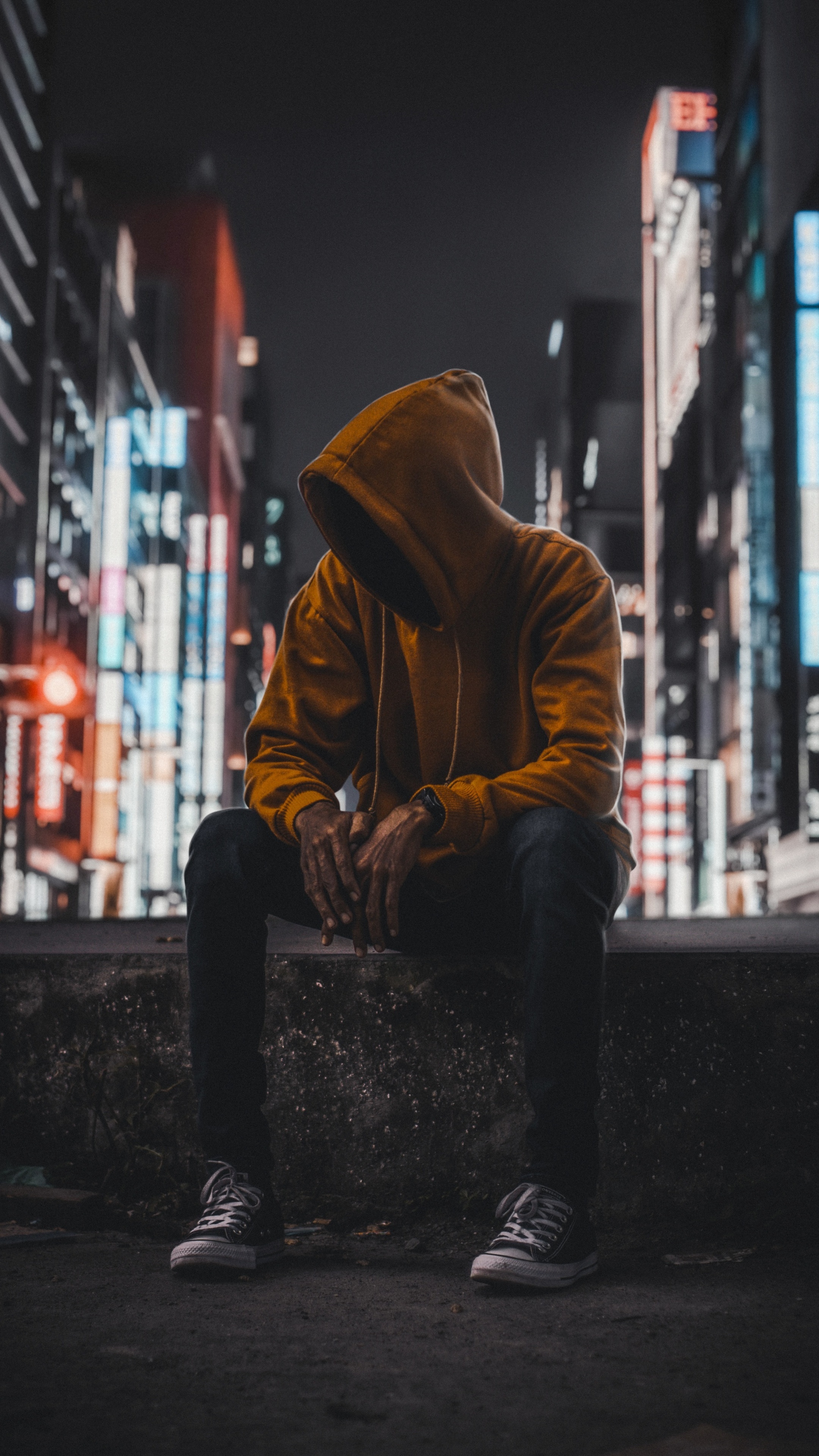 Person in hoodie sitting in a city at night HD Phone Wallpaper