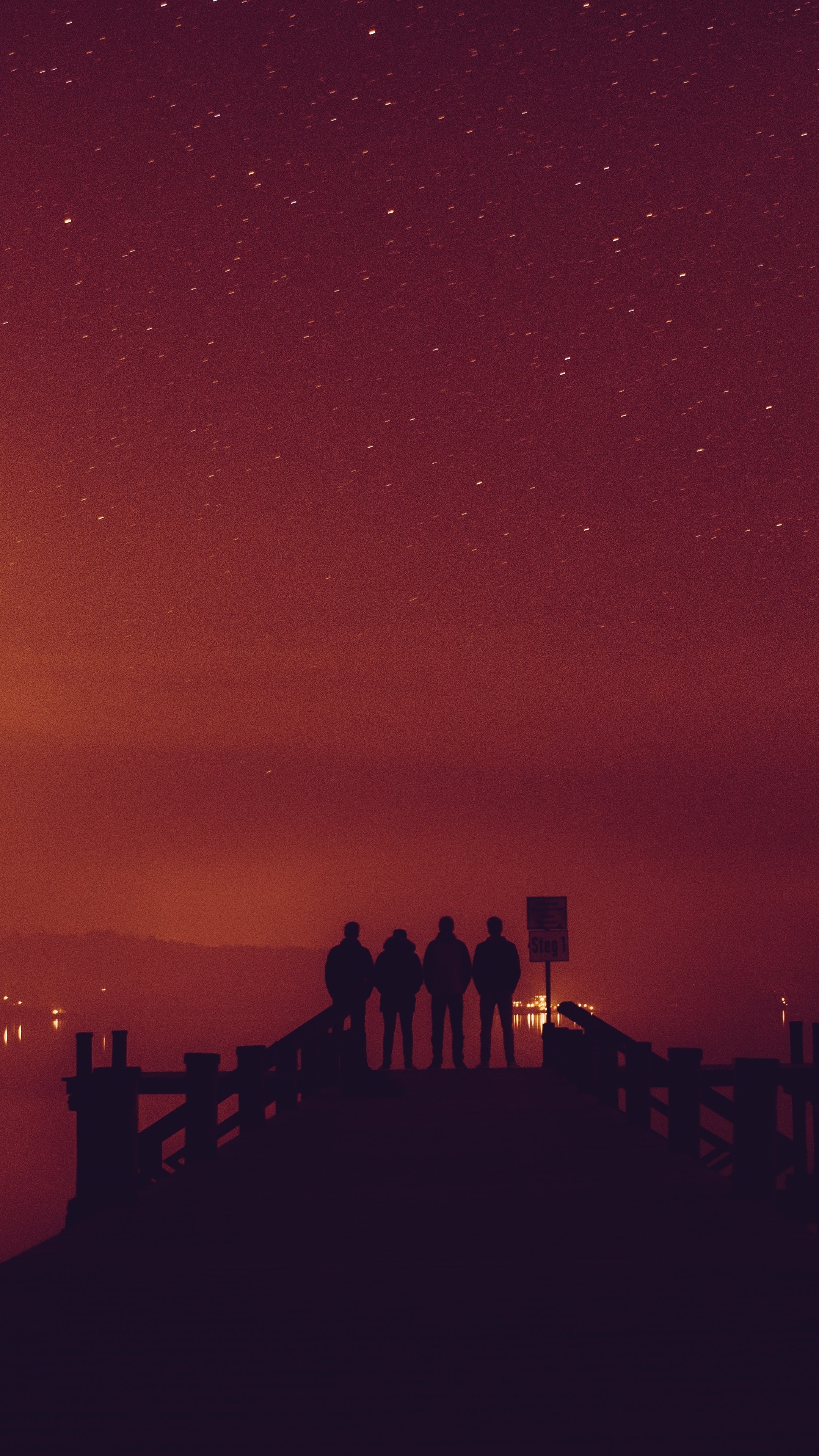 Four friends silhouetted on a pier at night HD Phone Wallpaper