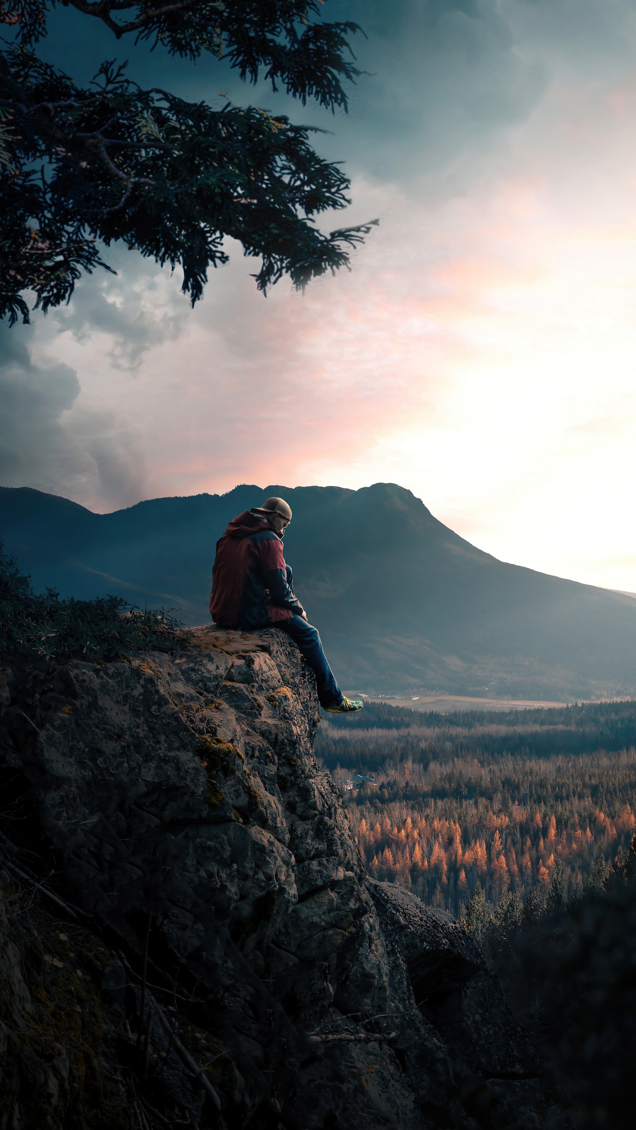 Man sitting on a cliff overlooking mountains HD Phone Wallpaper
