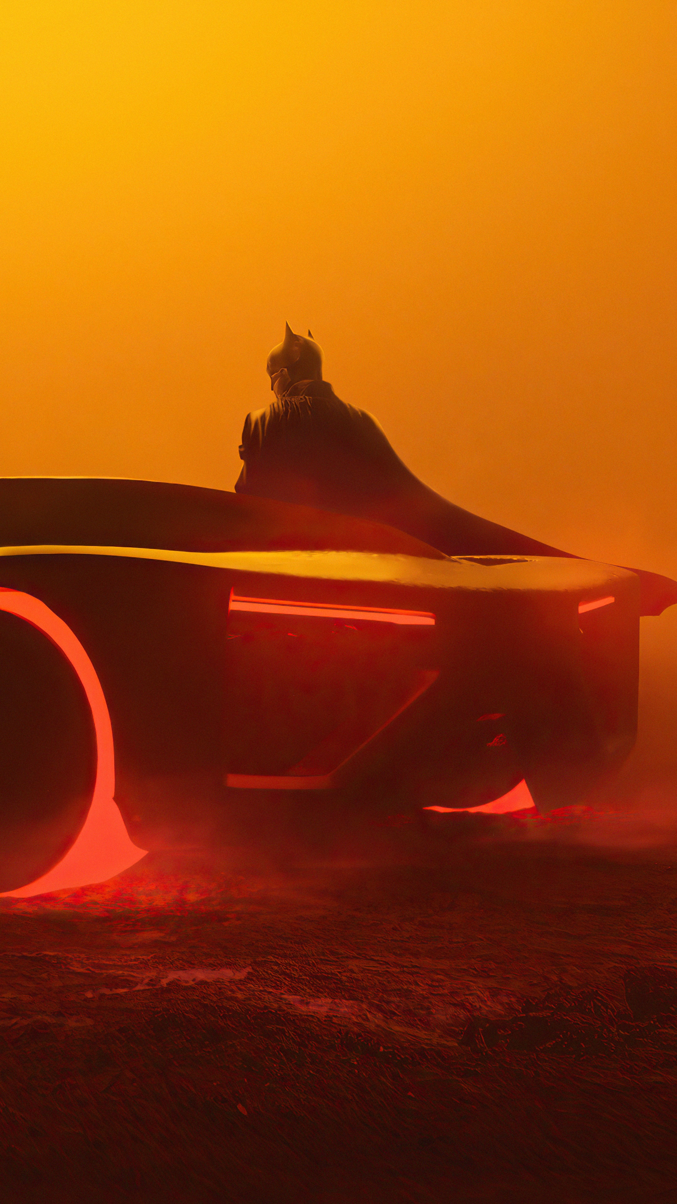 Batman sitting on the Batmobile in a foggy orange environment HD Phone Wallpaper