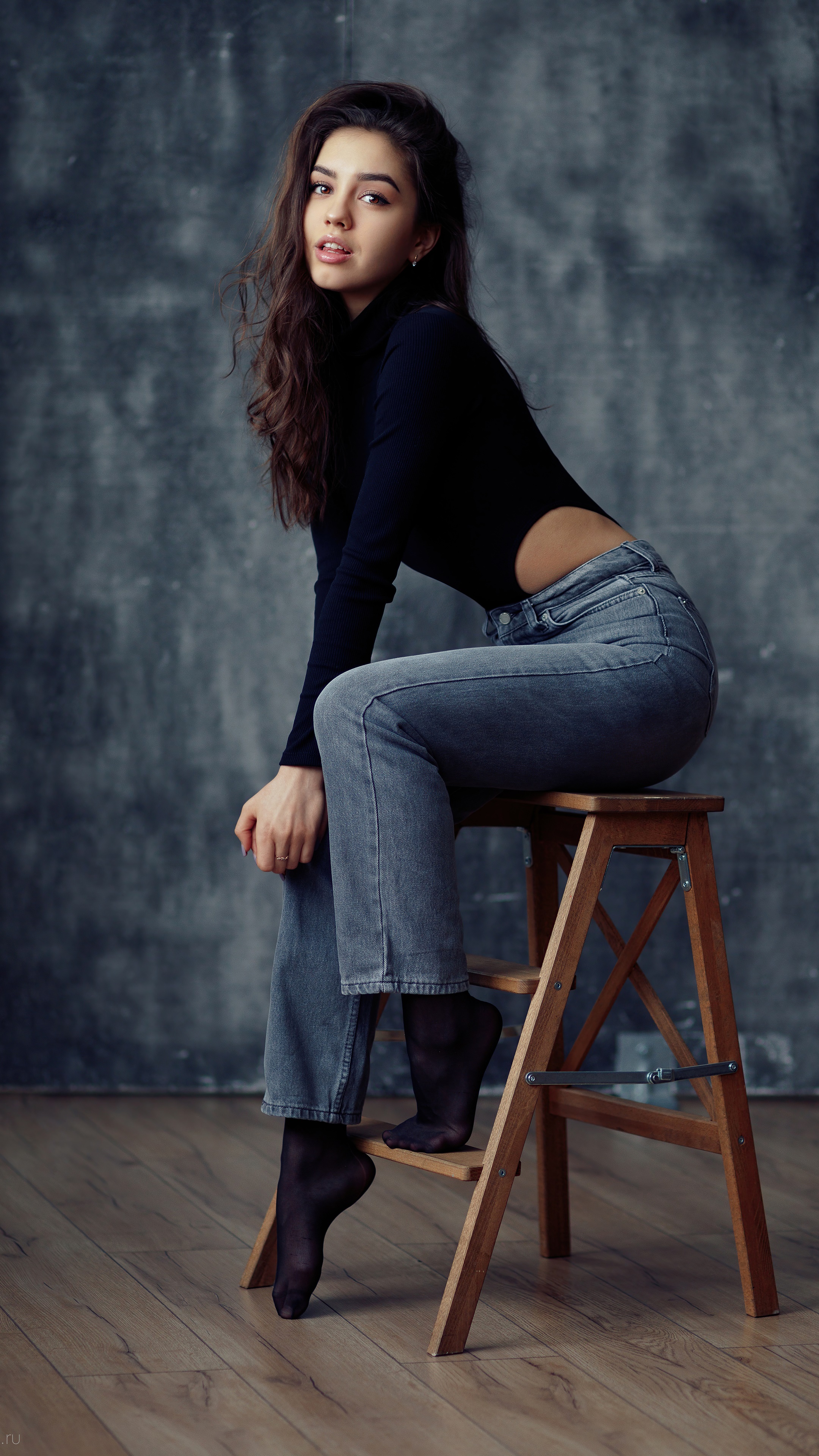 Woman in black turtleneck and jeans sitting on stool HD Phone Wallpaper