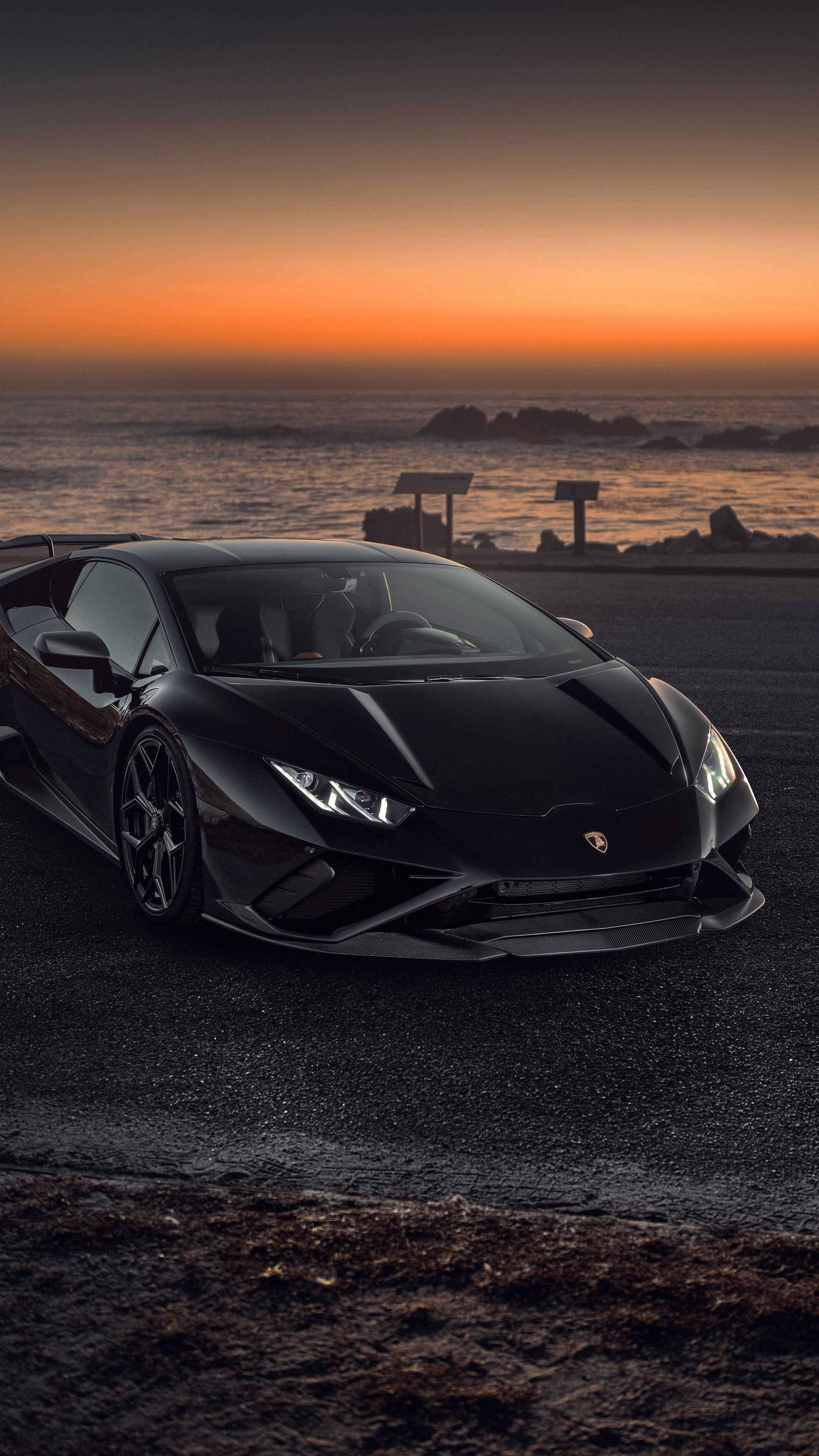 Black Lamborghini Huracan Evo parked by the ocean at sunset HD Phone Wallpaper