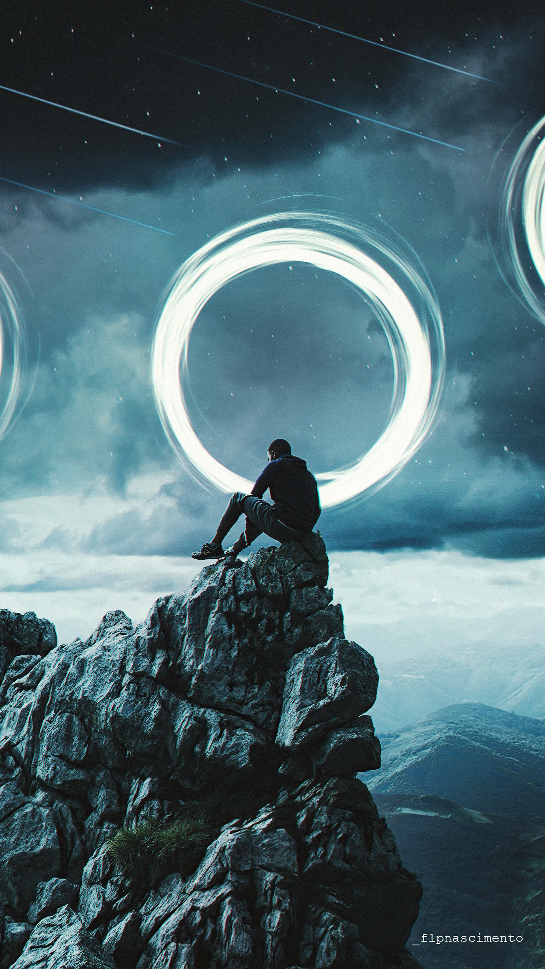 Man sitting on a mountain peak with glowing rings in the sky HD Phone Wallpaper