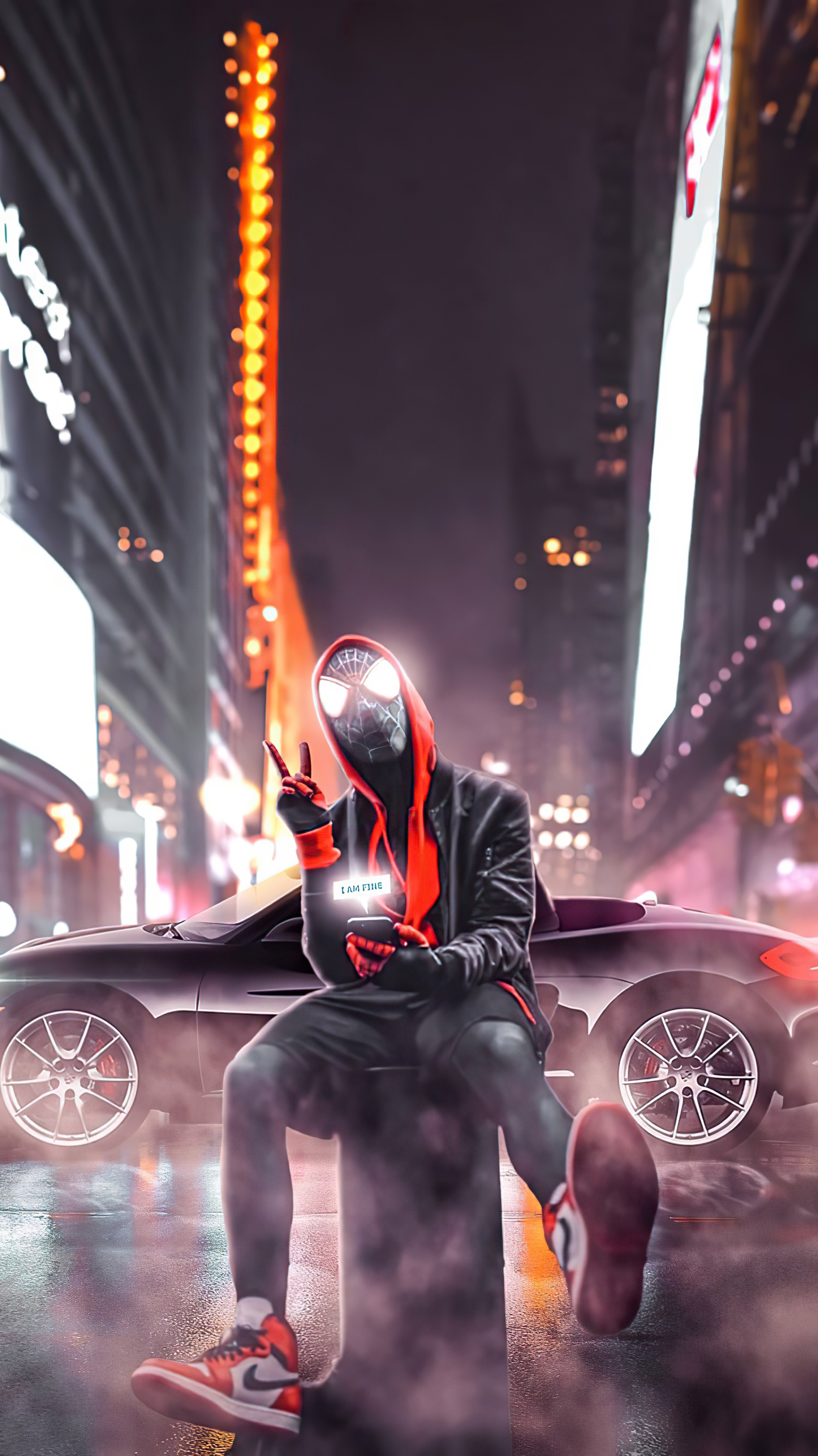 Spiderman sitting on a pillar with a car in the background HD Phone Wallpaper