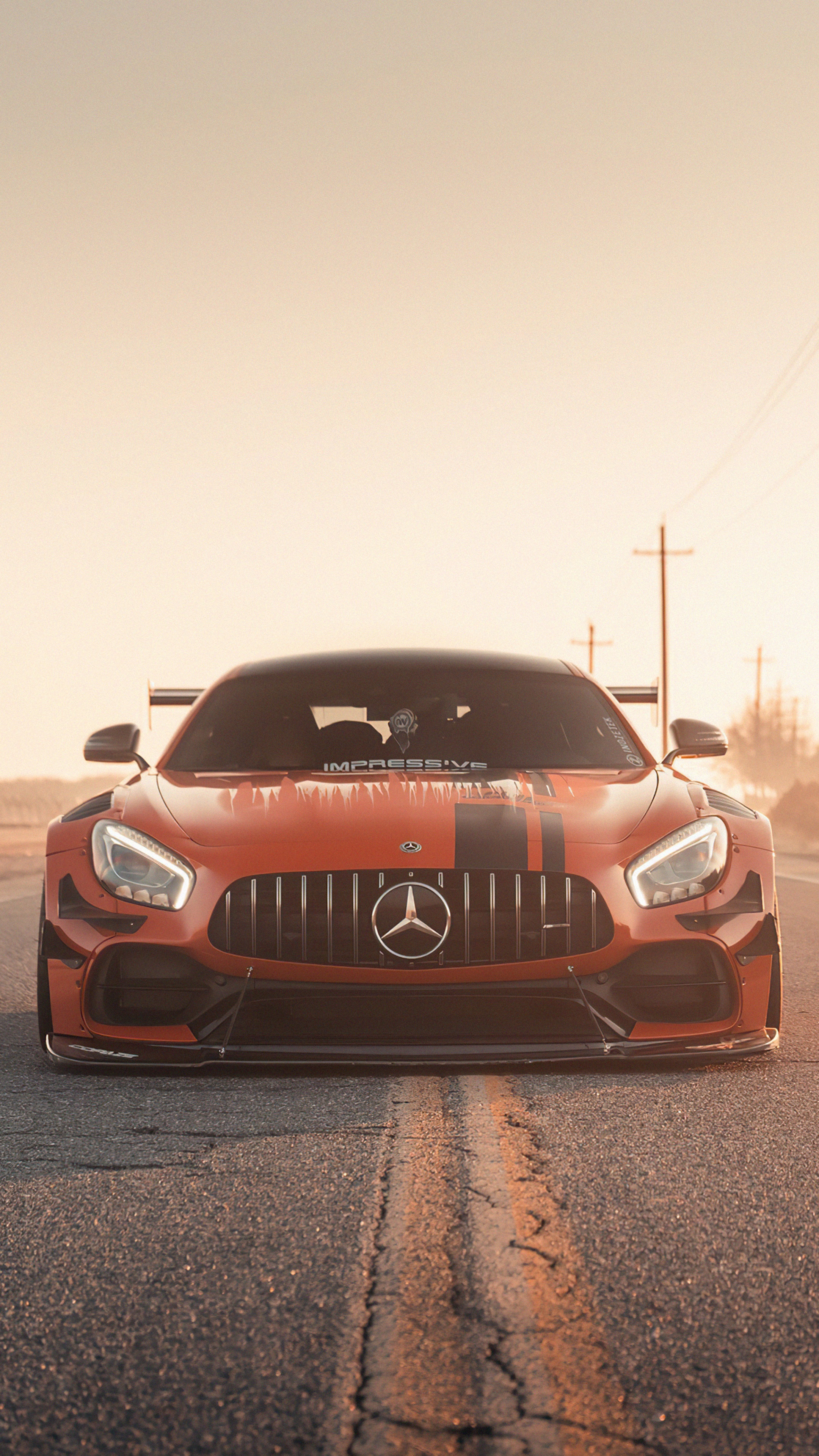 Orange Mercedes-AMG GT R with racing stripes on road HD Phone Wallpaper