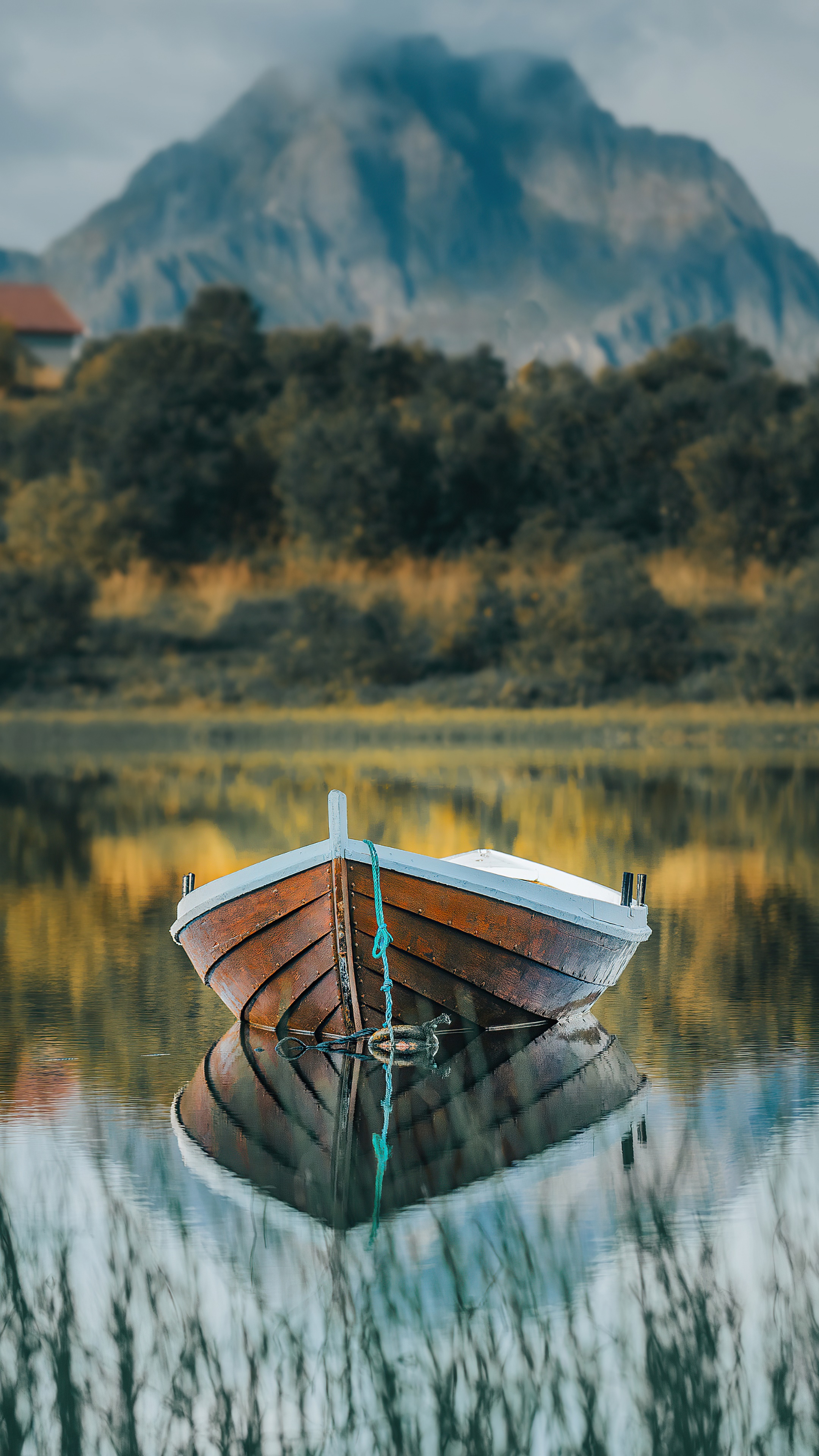Wooden boat reflected in calm water with mountain background HD Phone Wallpaper