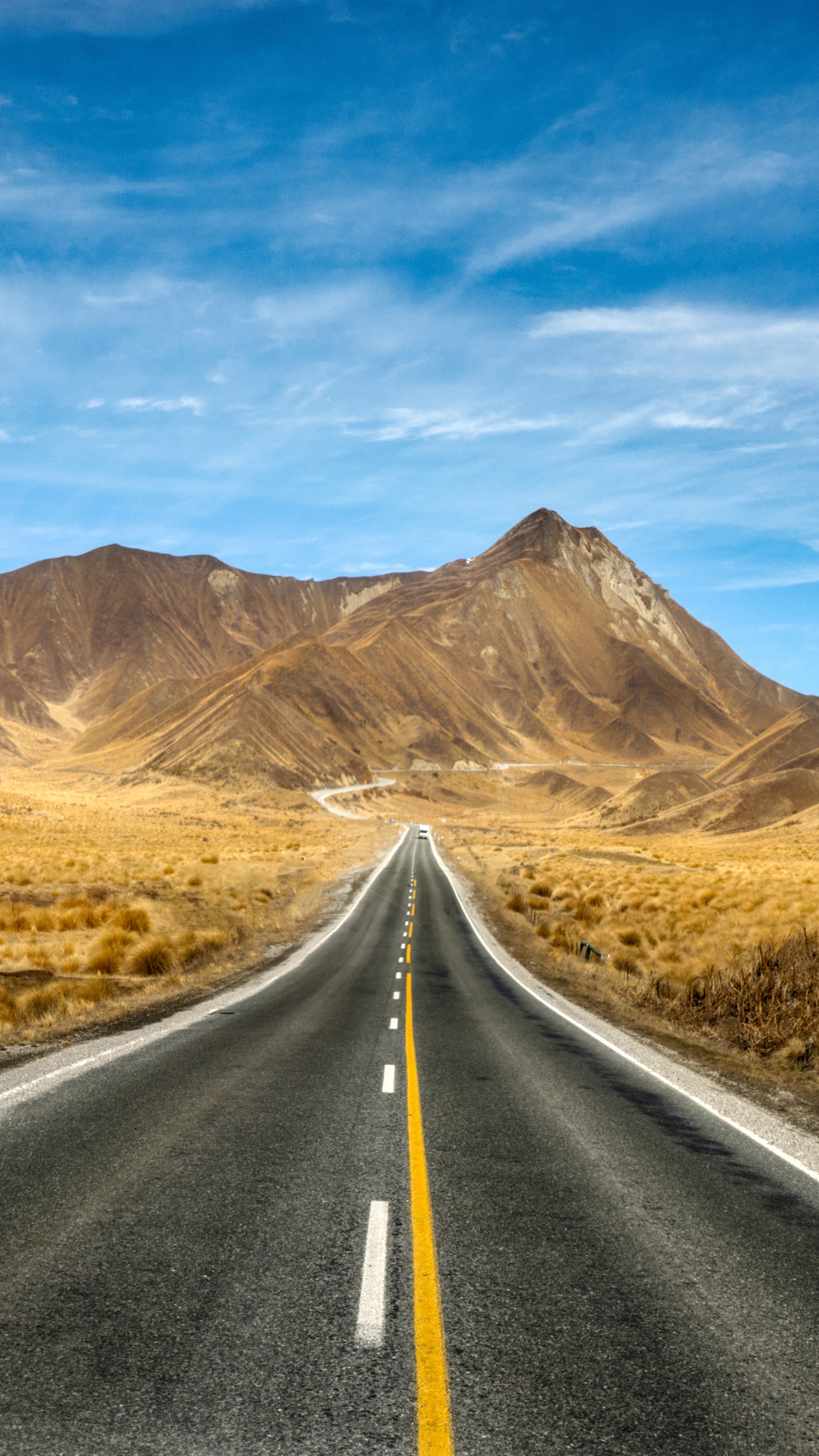Road through mountains under blue sky HD Phone Wallpaper