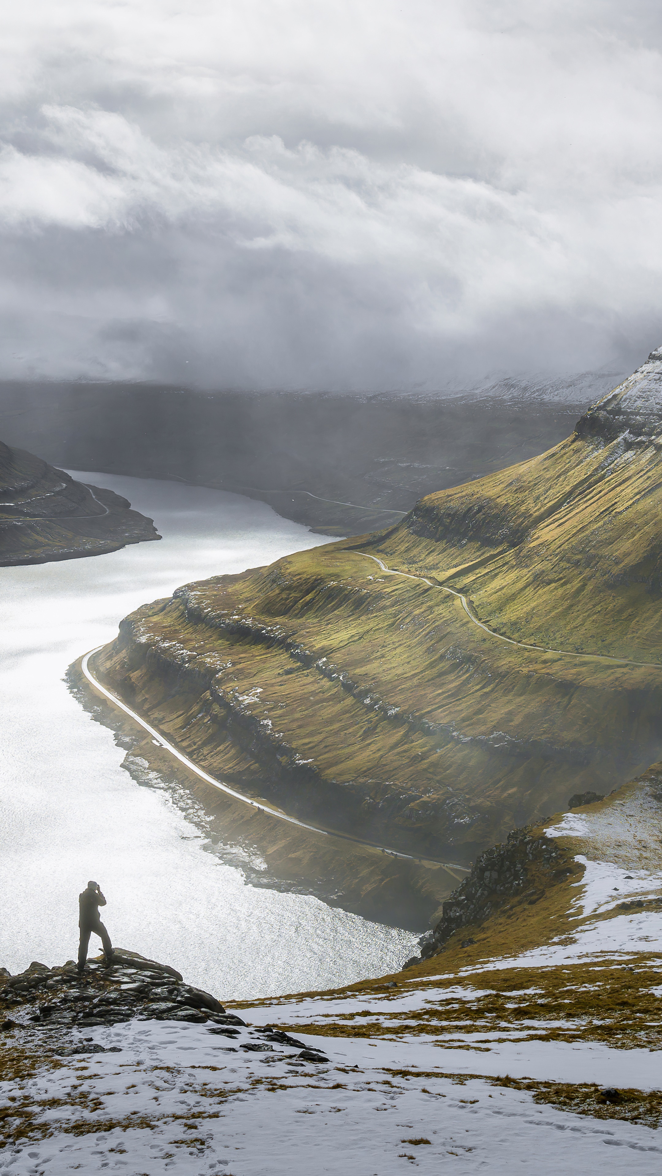 Photographer on cliff overlooking a fjord and mountains HD Phone Wallpaper