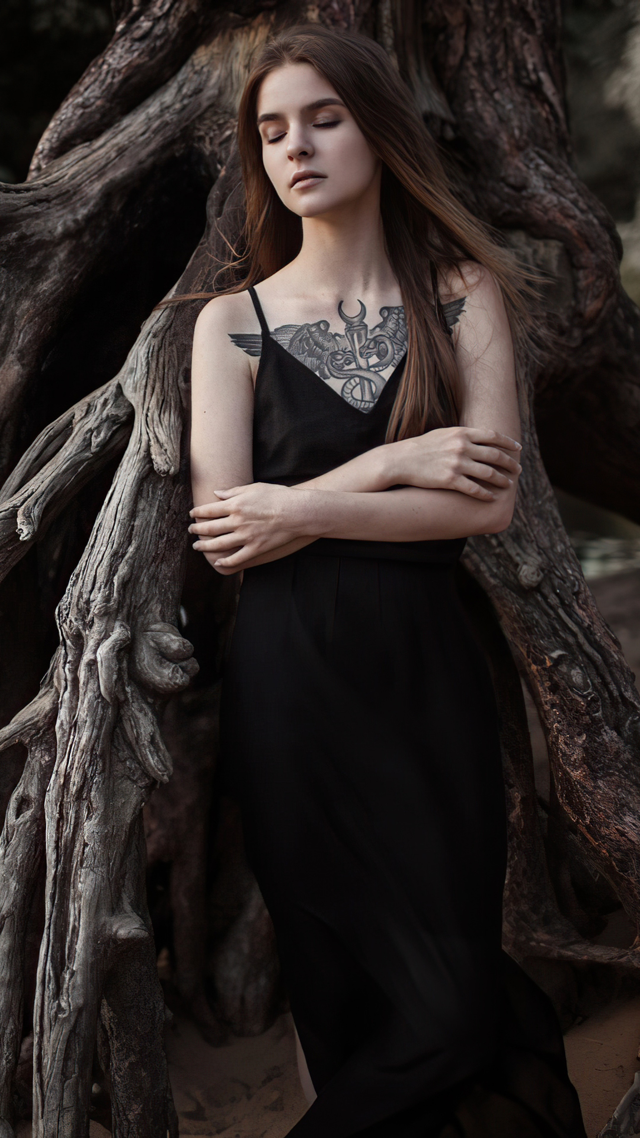 Woman with tattoo in black dress near tree roots HD Phone Wallpaper