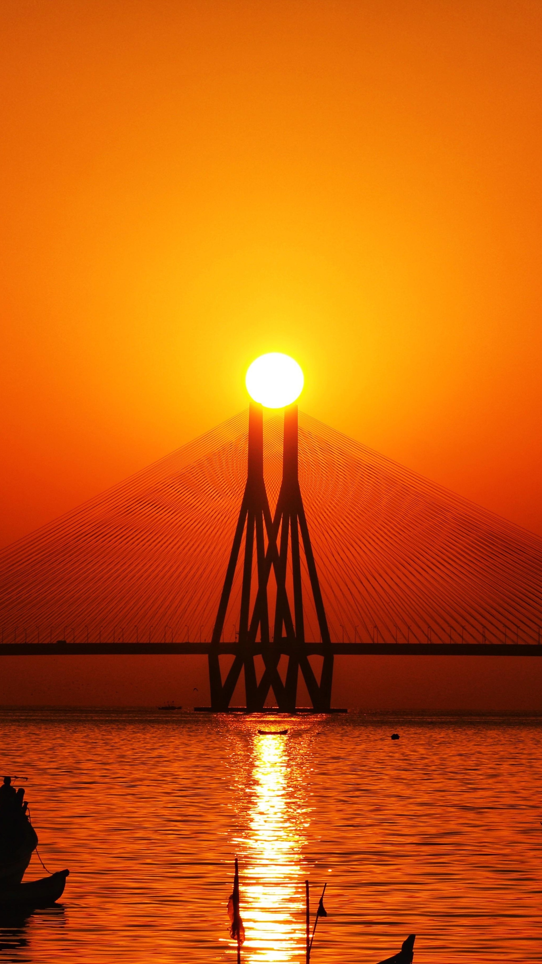 Sunset over a bridge with boats on the water HD Phone Wallpaper