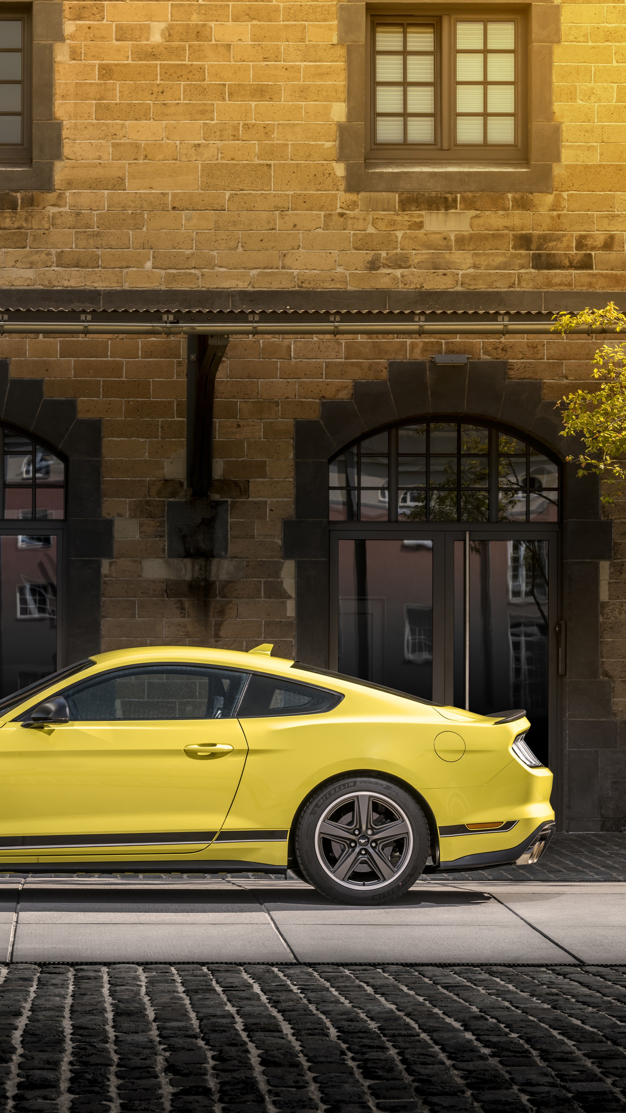 Yellow Ford Mustang parked in front of a brick building HD Phone Wallpaper