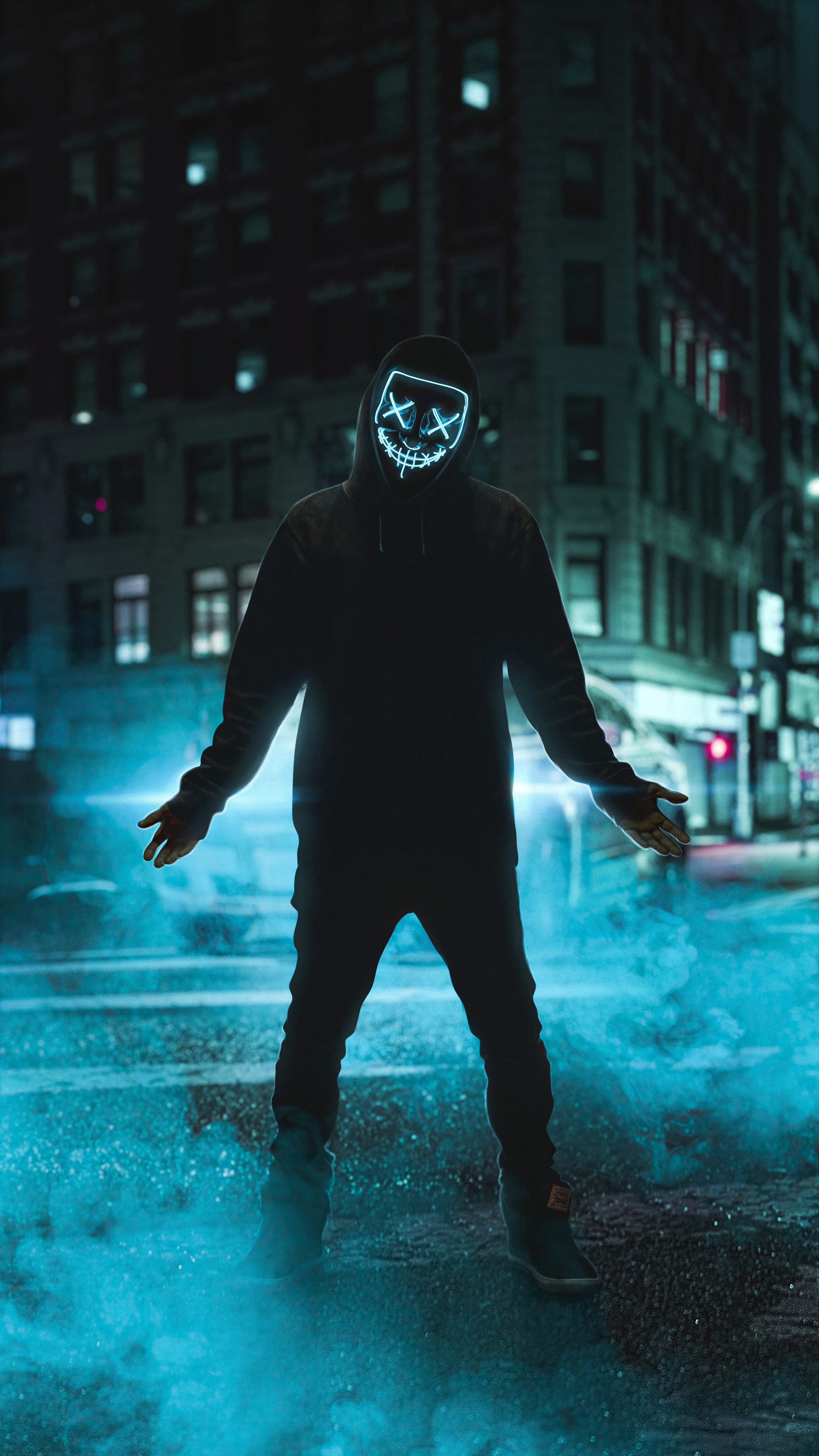 Man in Anonymous mask with blue light in city at night HD Phone Wallpaper