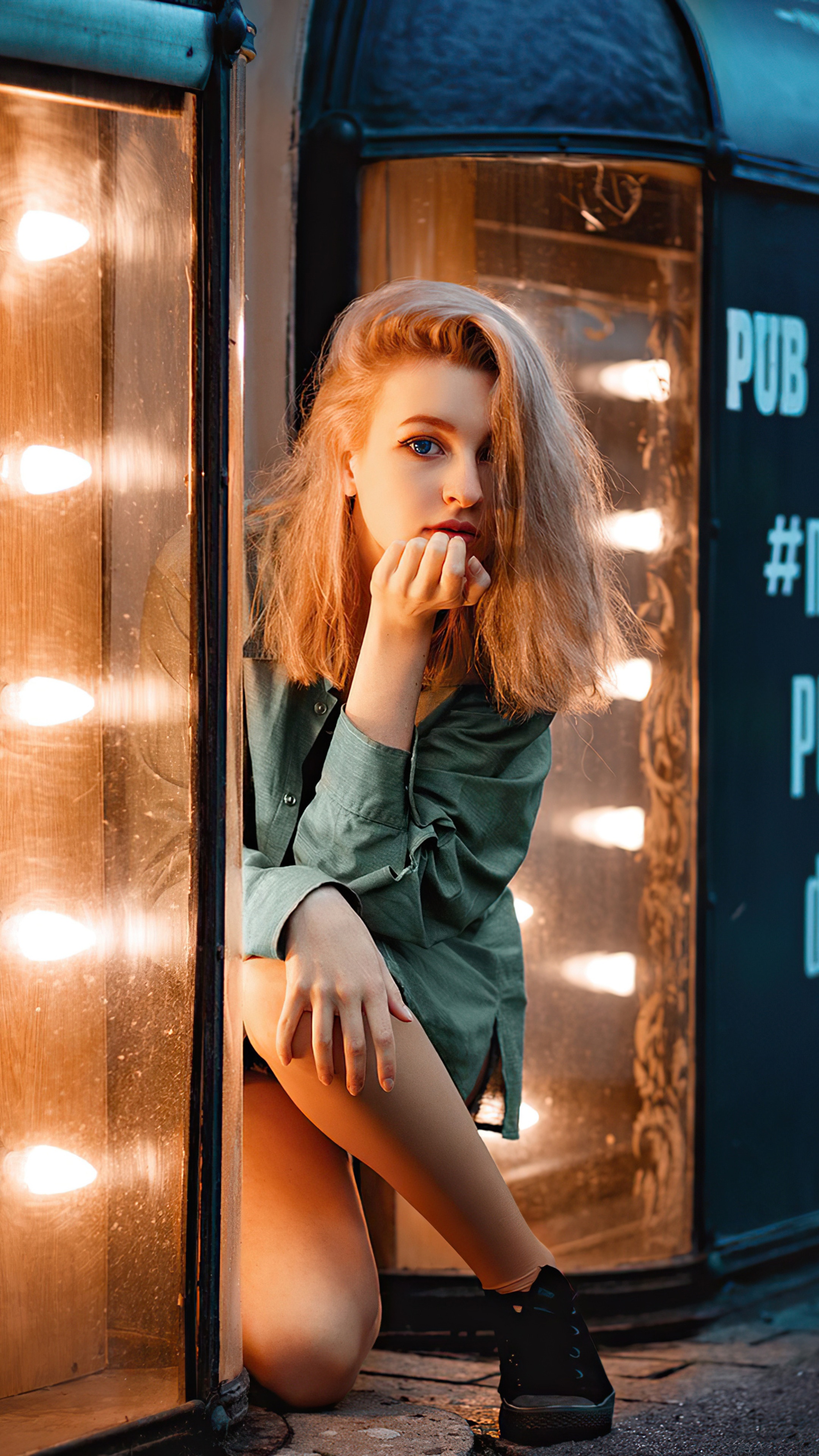 Girl in green shirt posing by illuminated storefront HD Phone Wallpaper
