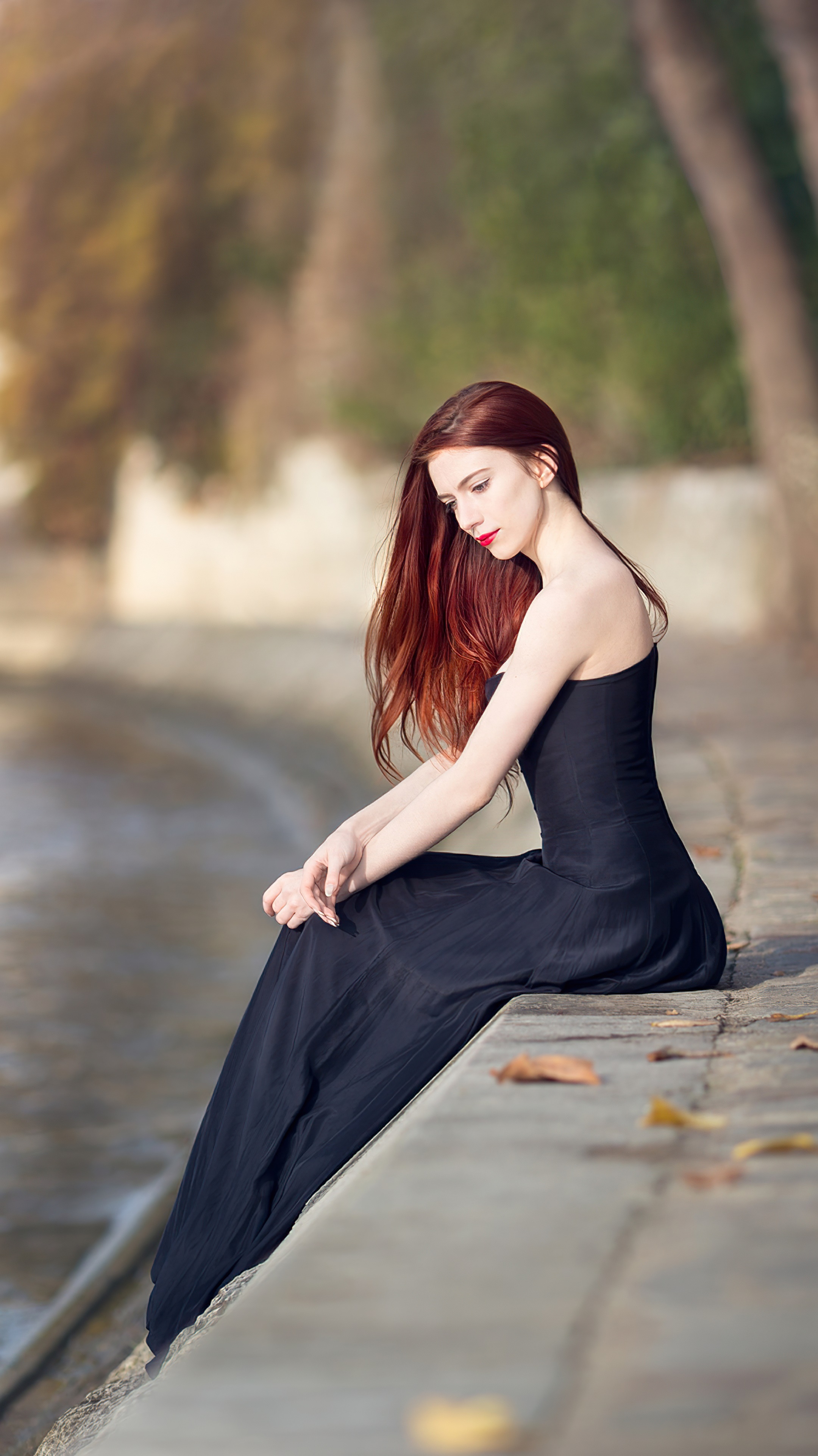 Woman in black dress sitting by water HD Phone Wallpaper