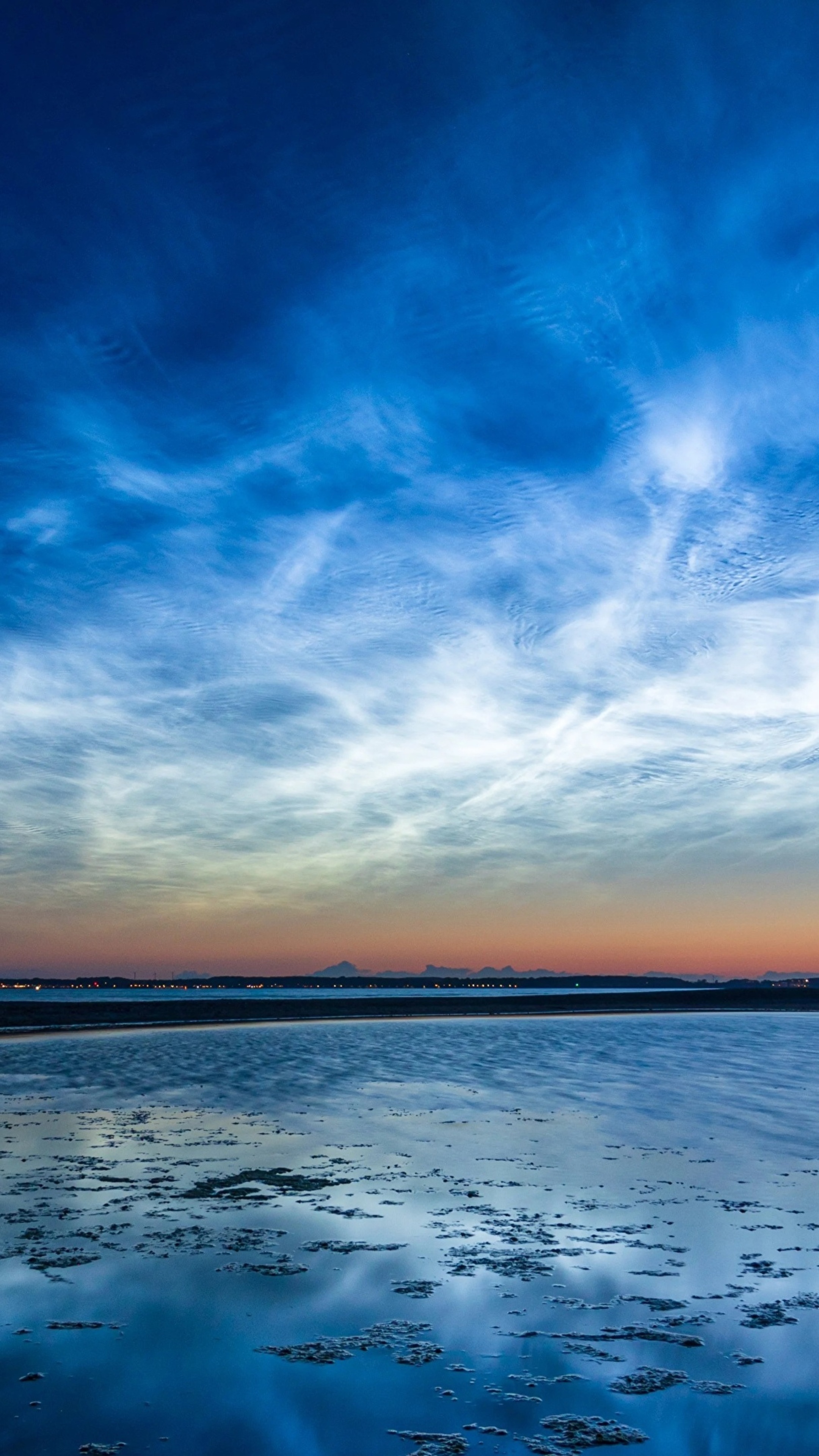 Noctilucent clouds over a body of water at dusk HD Phone Wallpaper