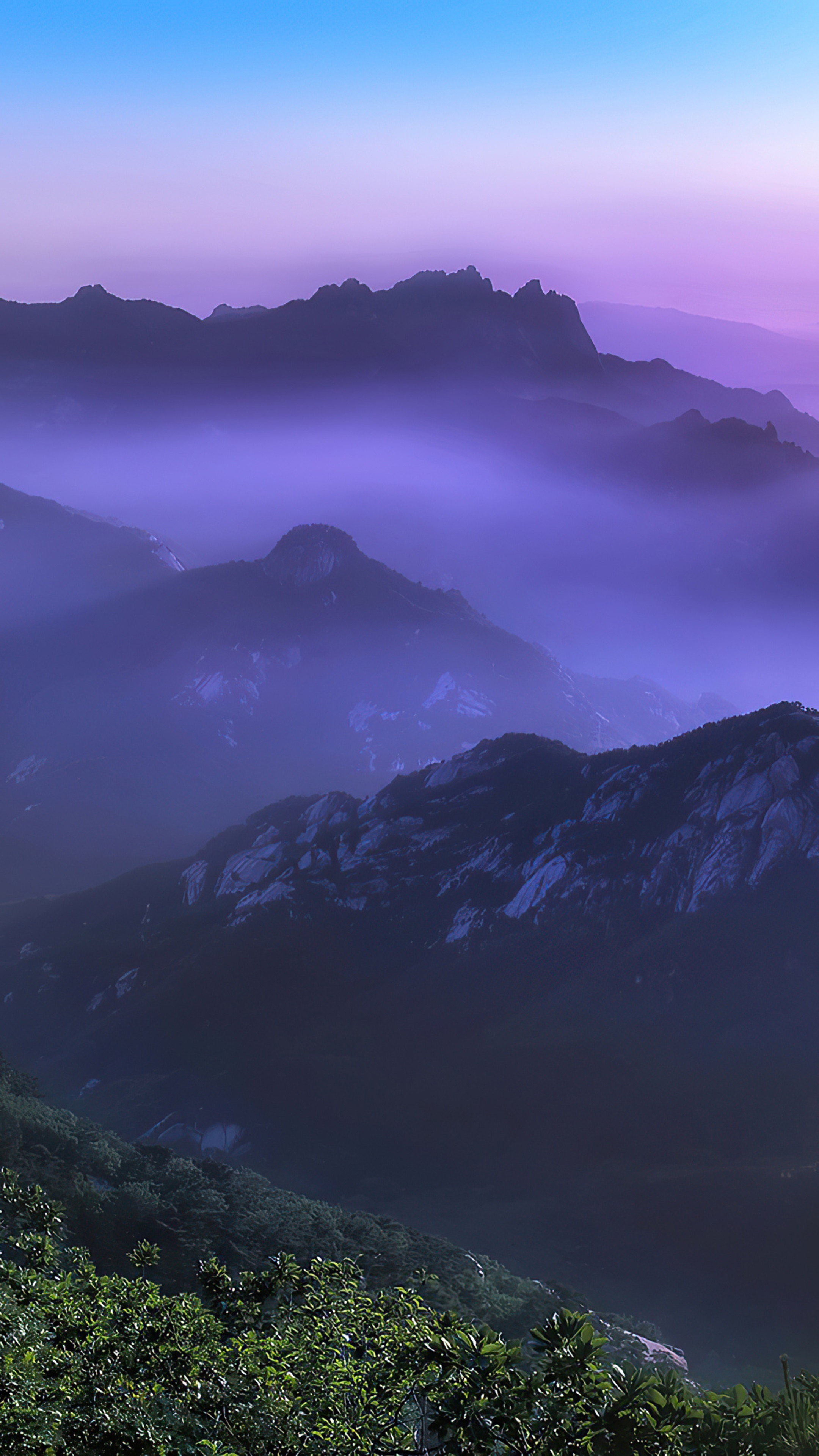 Mountains shrouded in purple mist under a blue and purple sky HD Phone Wallpaper