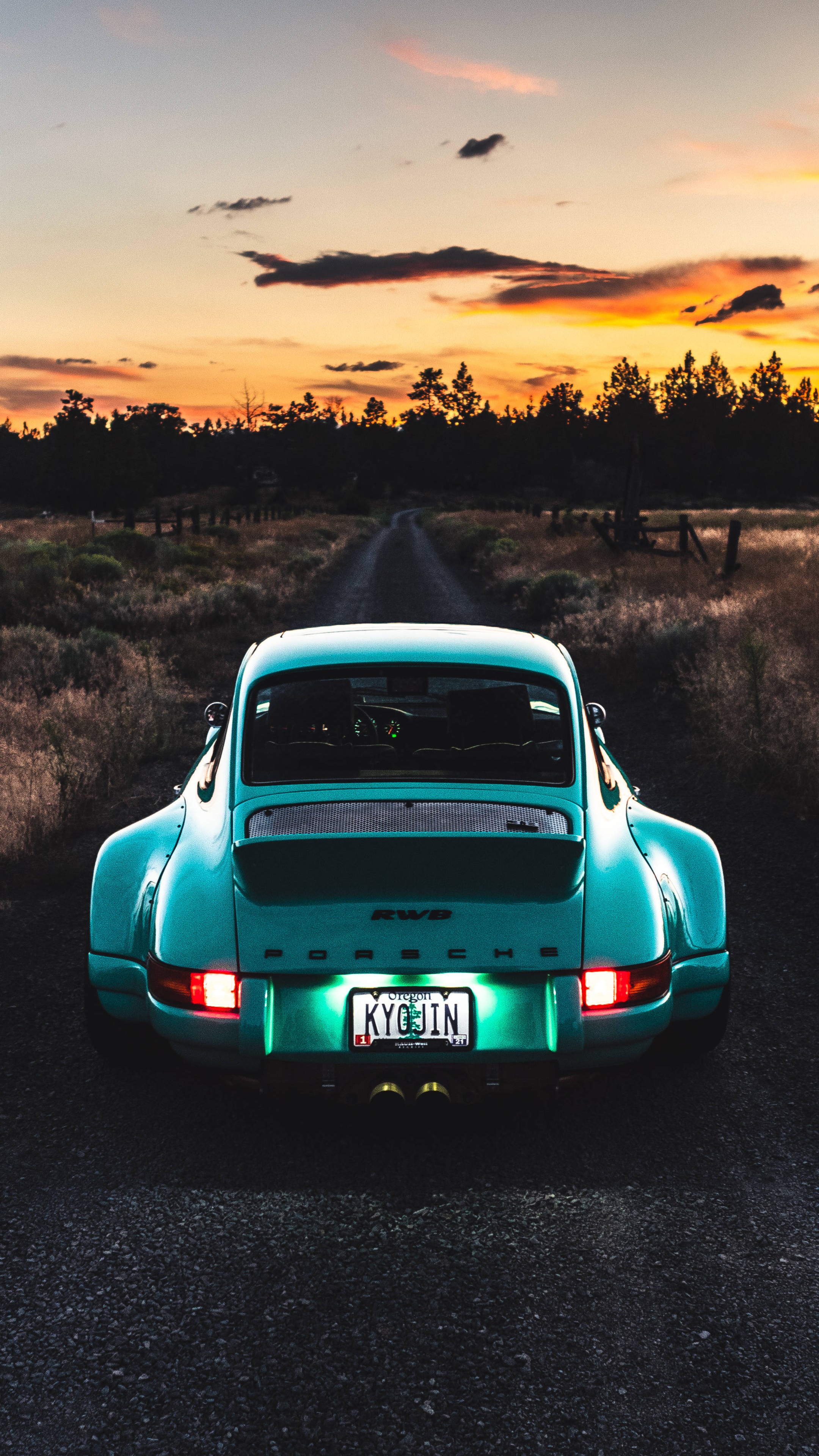 Rear view of a teal Porsche 911 on a dirt road at sunset HD Phone Wallpaper