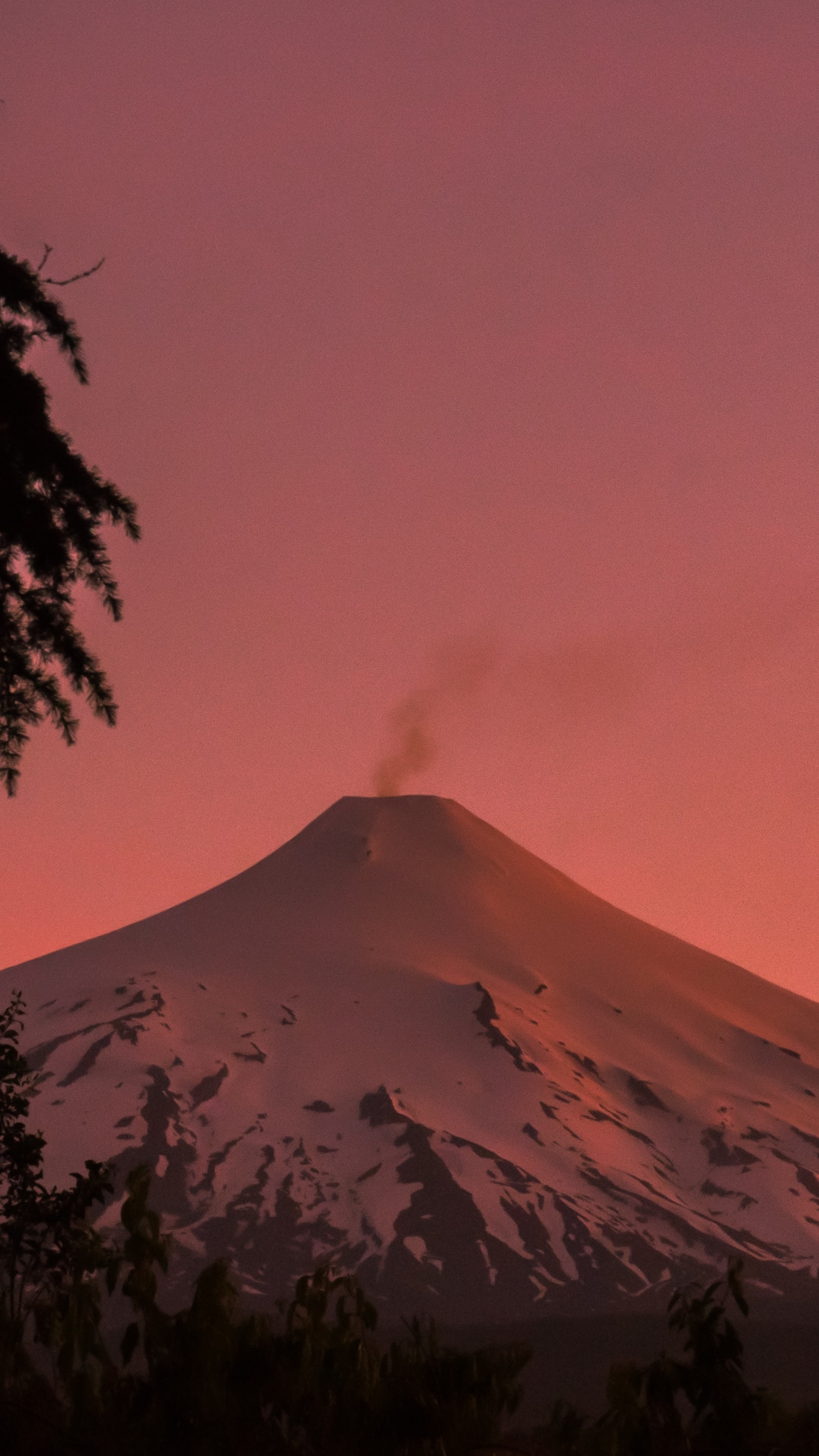 Snow-capped volcano emitting smoke at sunset HD Phone Wallpaper