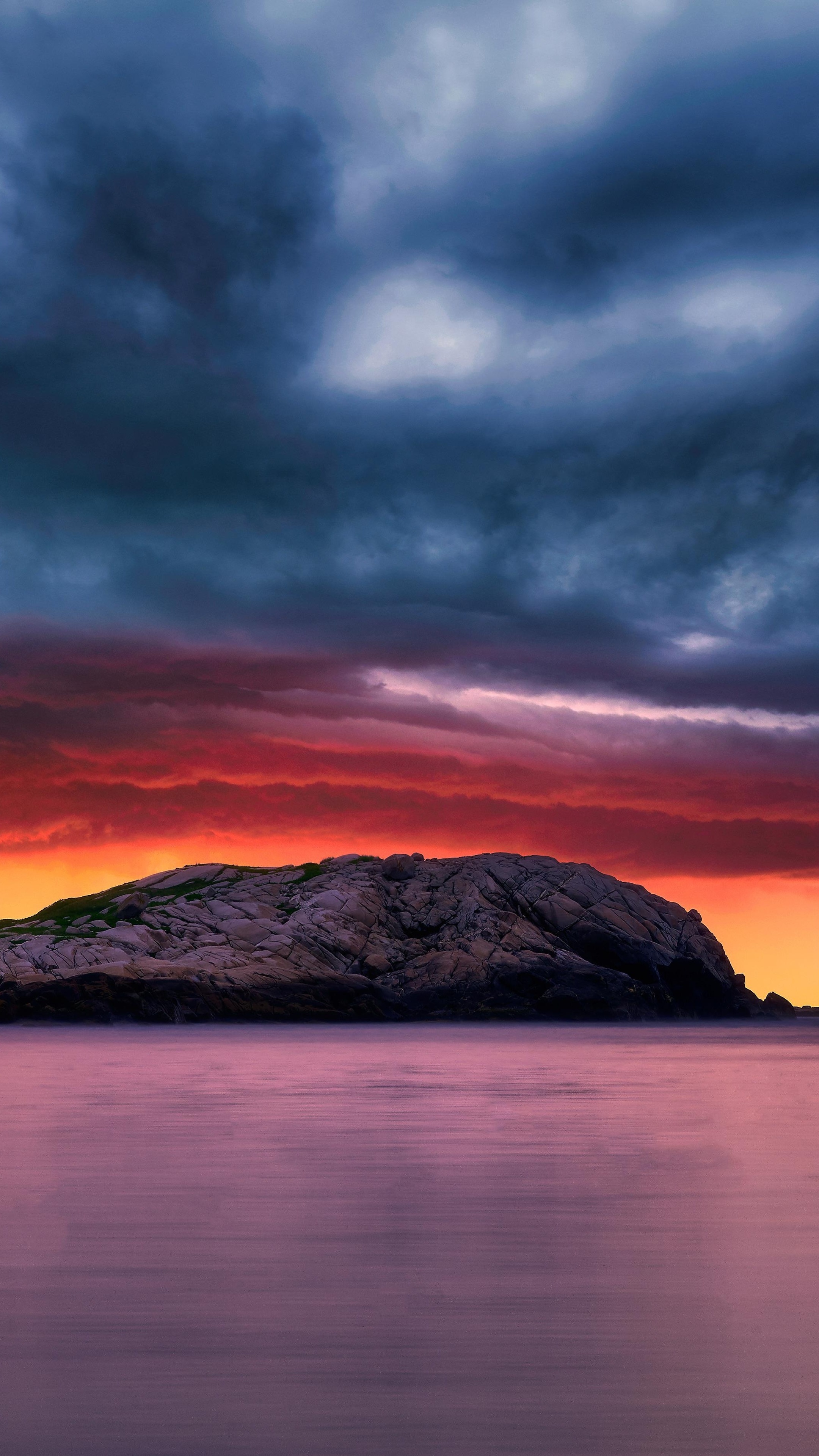 Rocky island in ocean during sunset with dramatic clouds 4K HD Phone Wallpaper