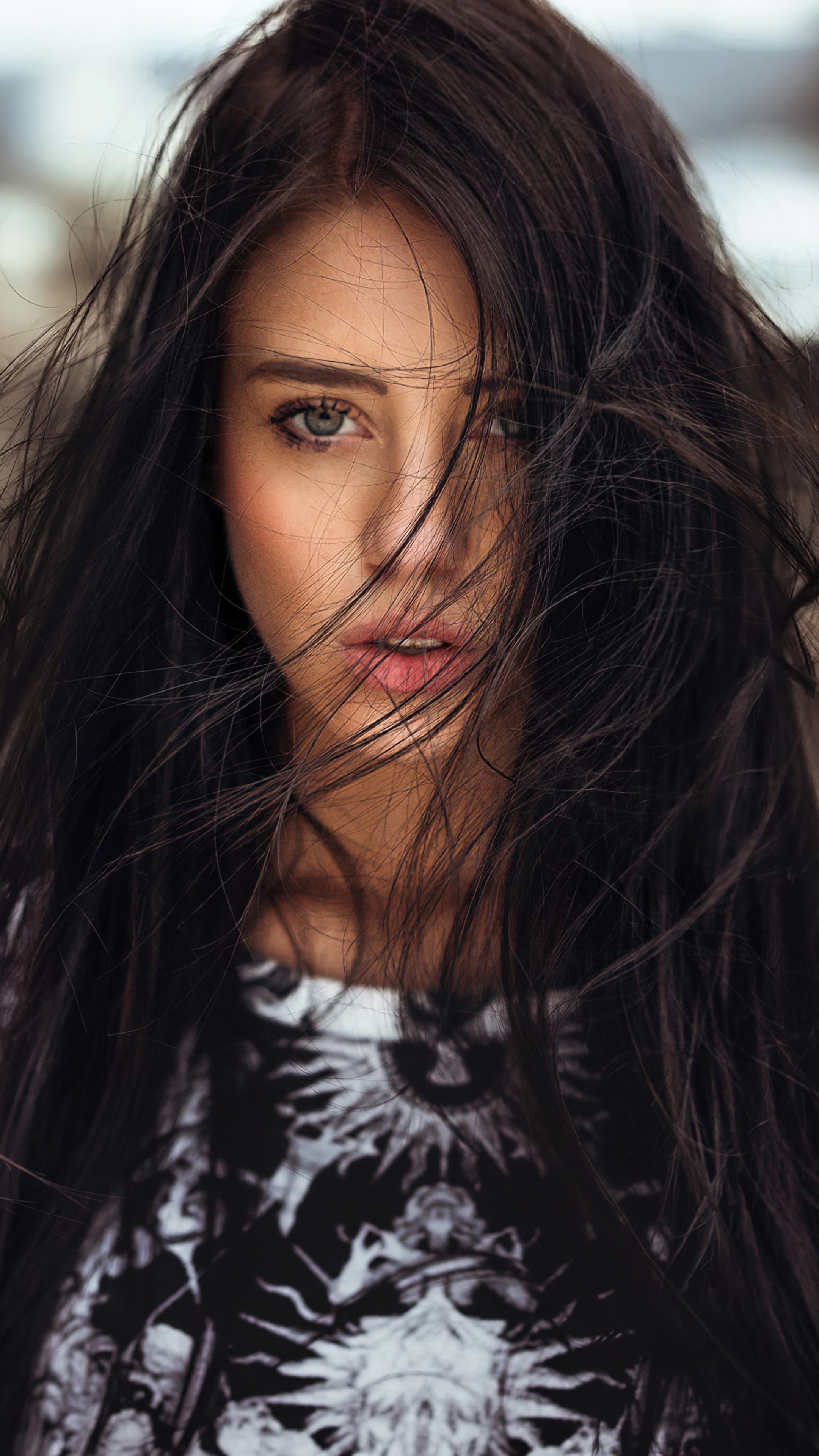 Woman with dark hair blowing in the wind HD Phone Wallpaper