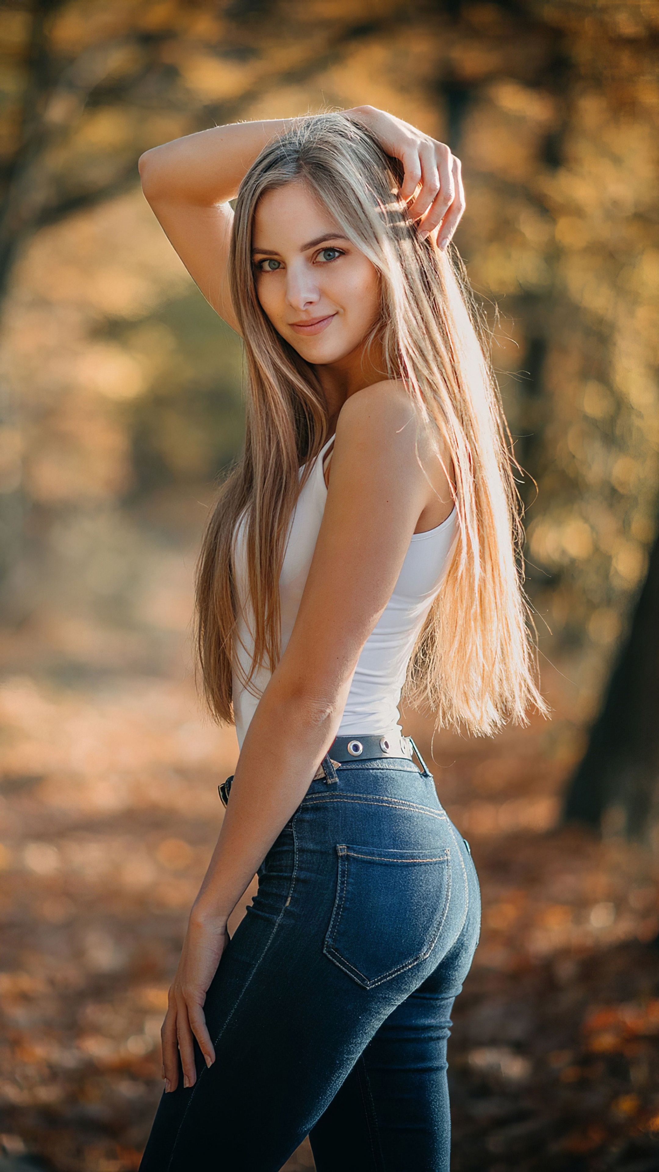 Woman in white tank top and jeans in autumn park HD Phone Wallpaper
