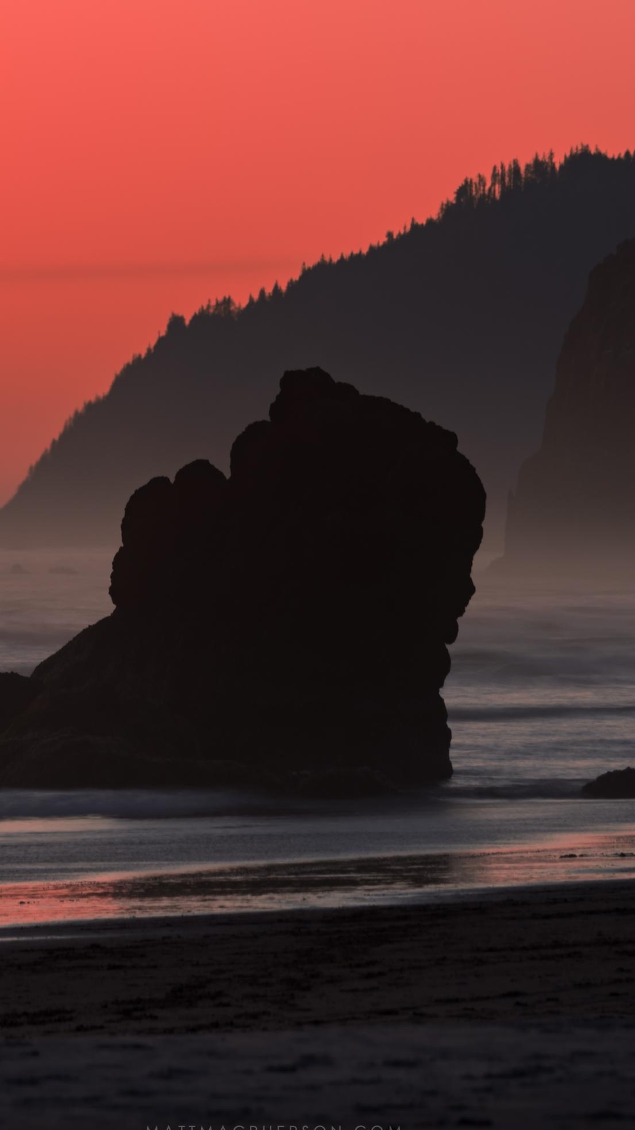 Silhouette of a rock formation on a beach at sunset HD Phone Wallpaper