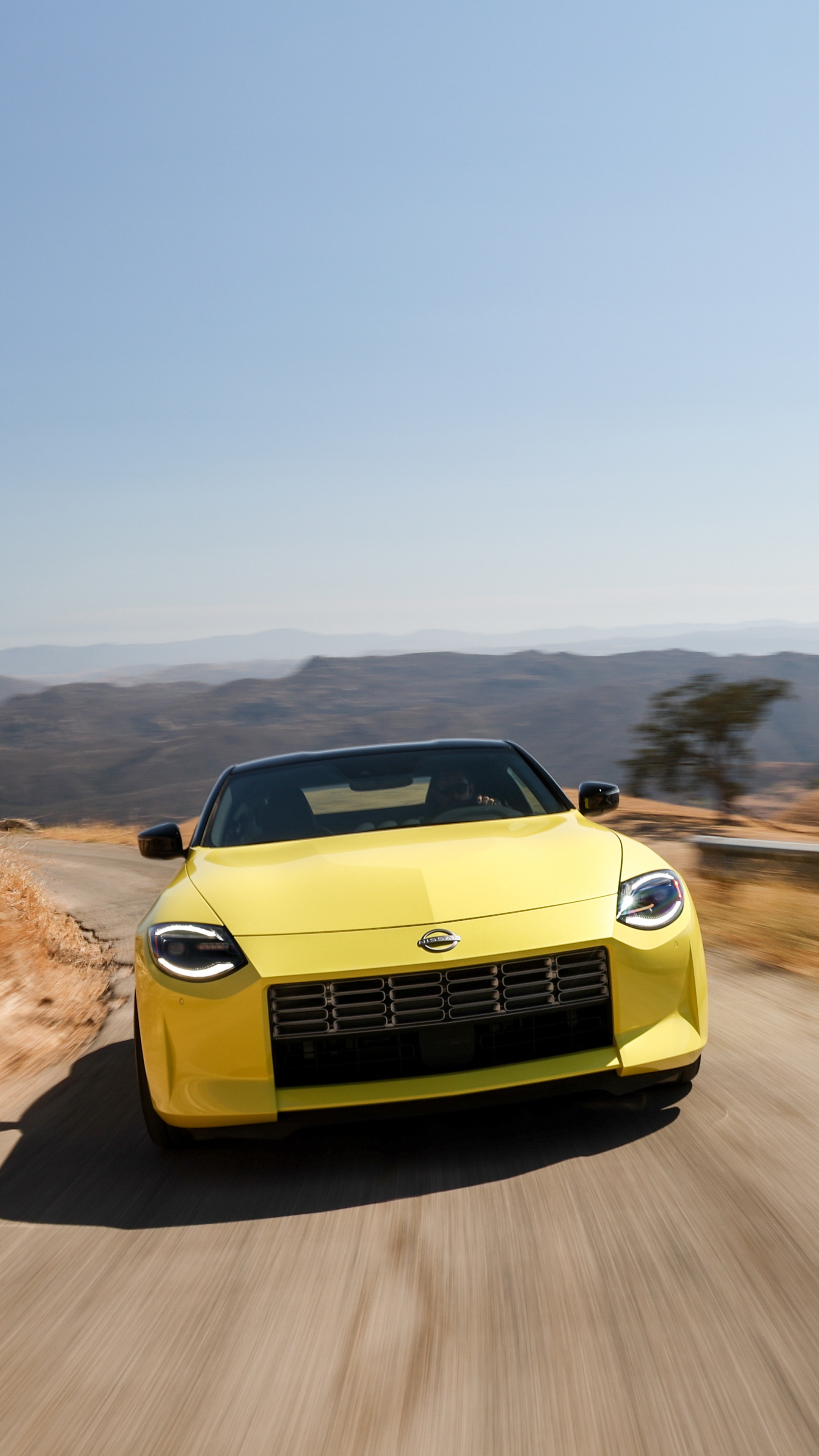 Yellow 2023 Nissan Z driving on a mountain road HD Phone Wallpaper