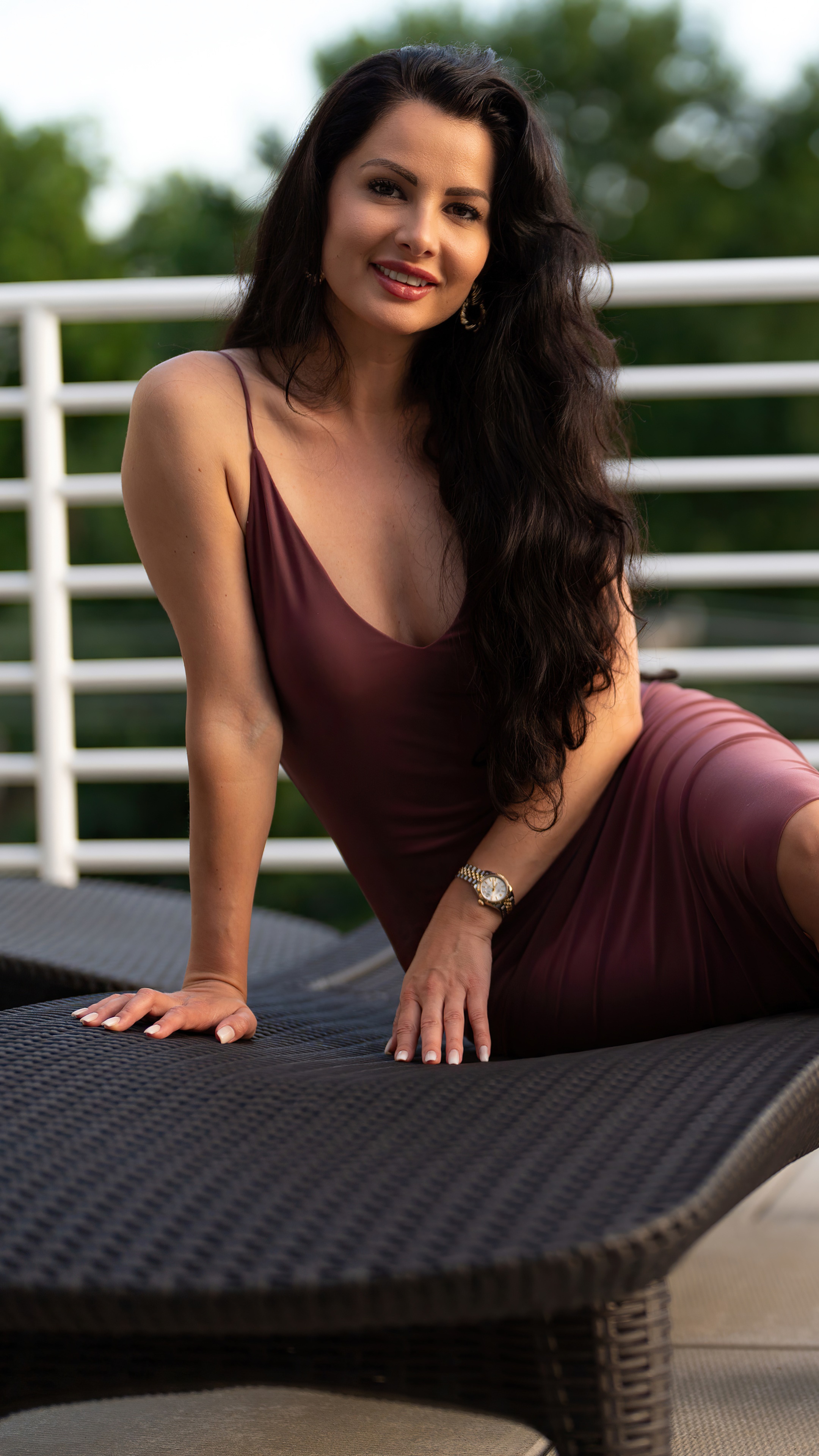 Brunette model in a dress on a lounge chair HD Phone Wallpaper