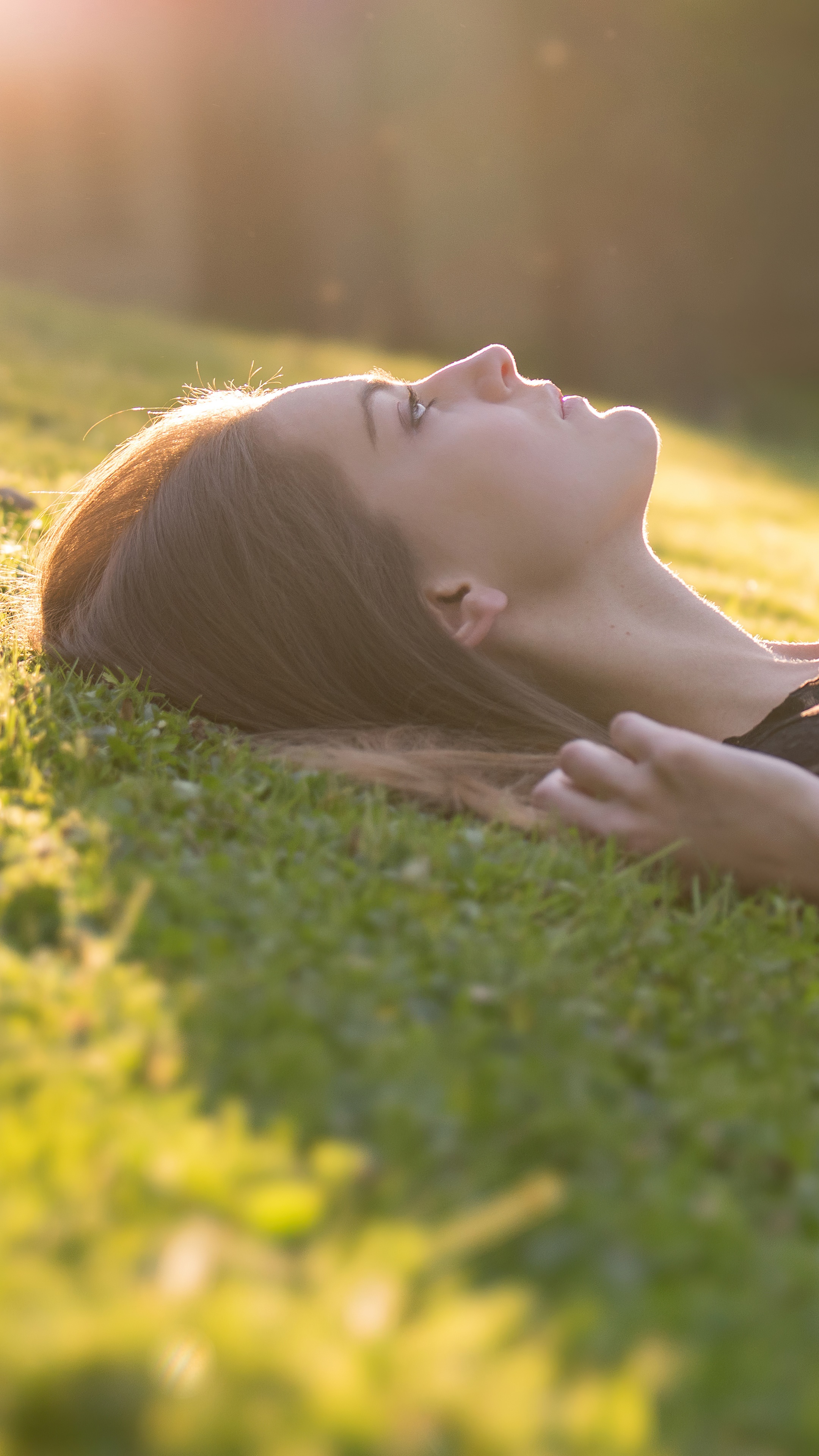 Young woman lying on grass in sunlight HD Phone Wallpaper
