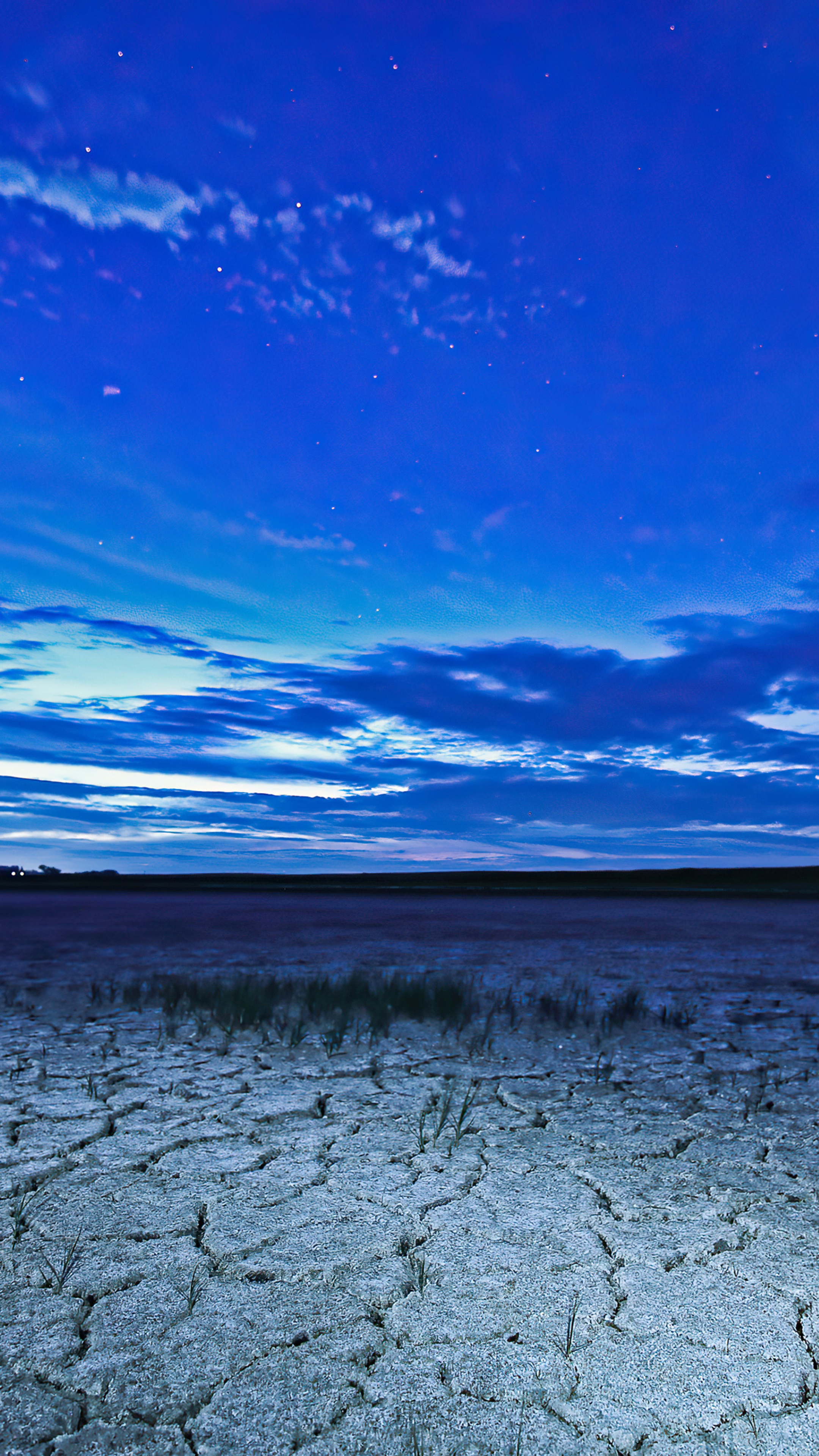 Cracked earth under a starry blue sky HD Phone Wallpaper