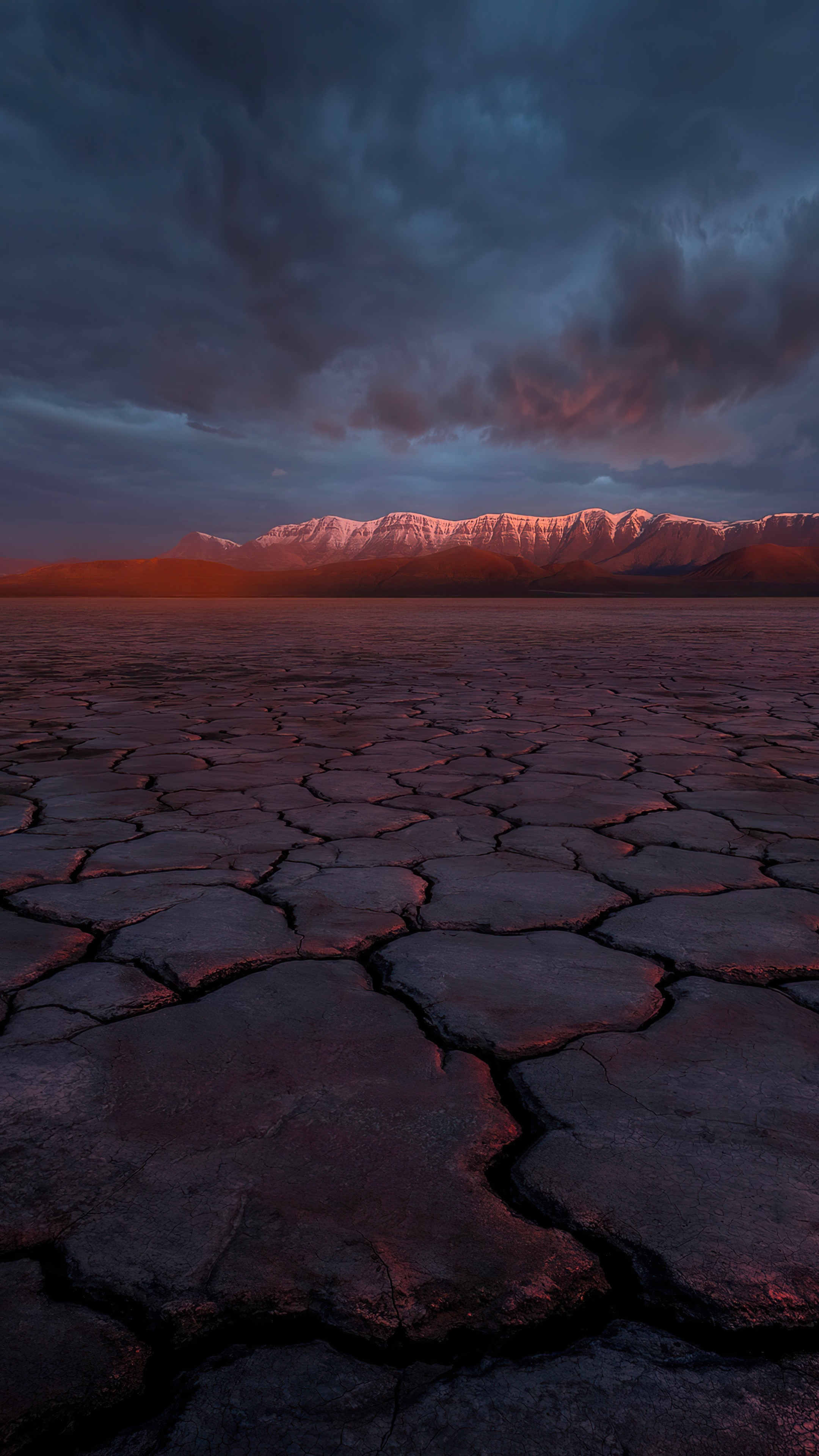 Cracked desert landscape with mountains at sunset HD Phone Wallpaper