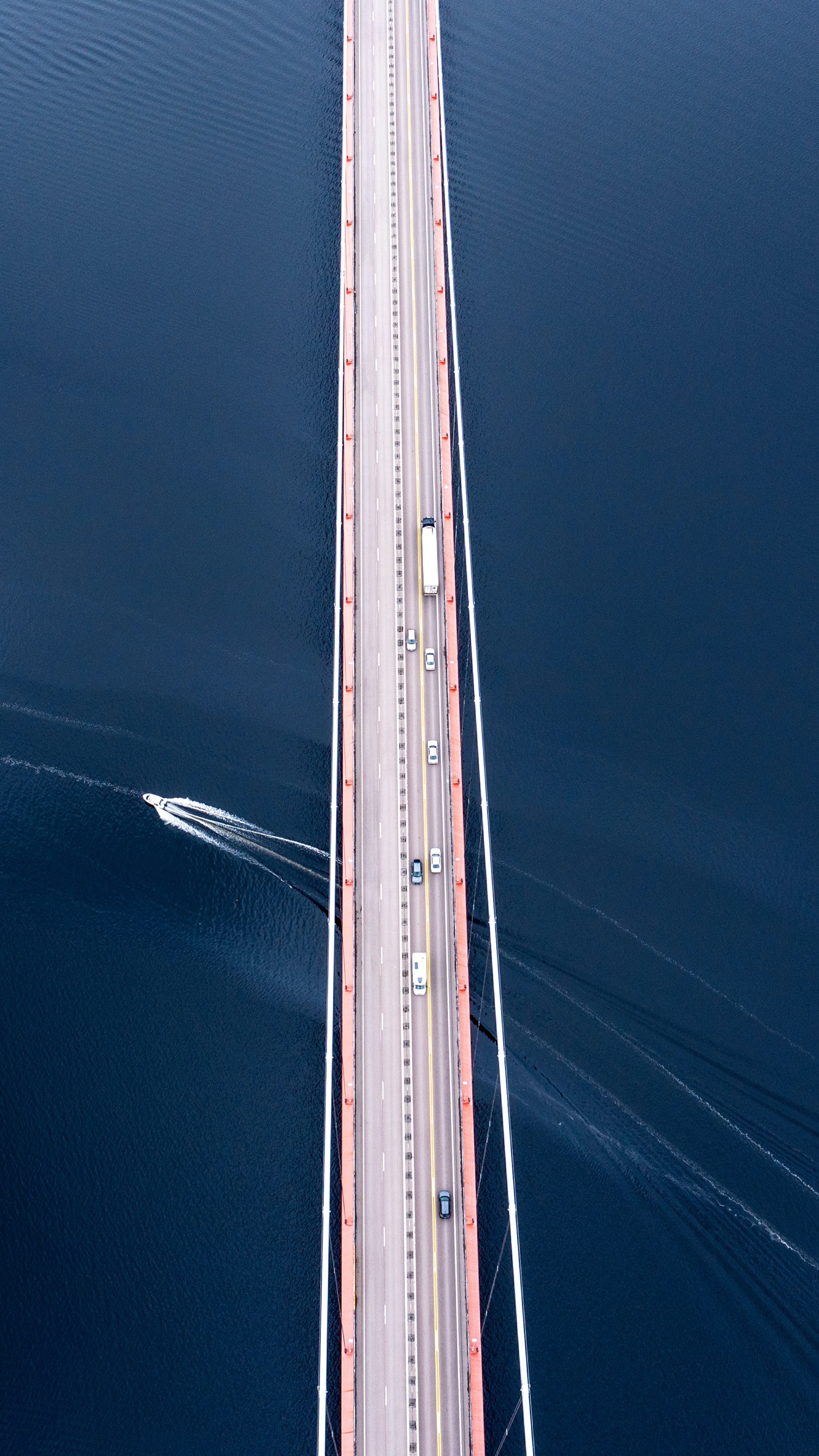Aerial view of a suspension bridge with traffic and a boat HD Phone Wallpaper